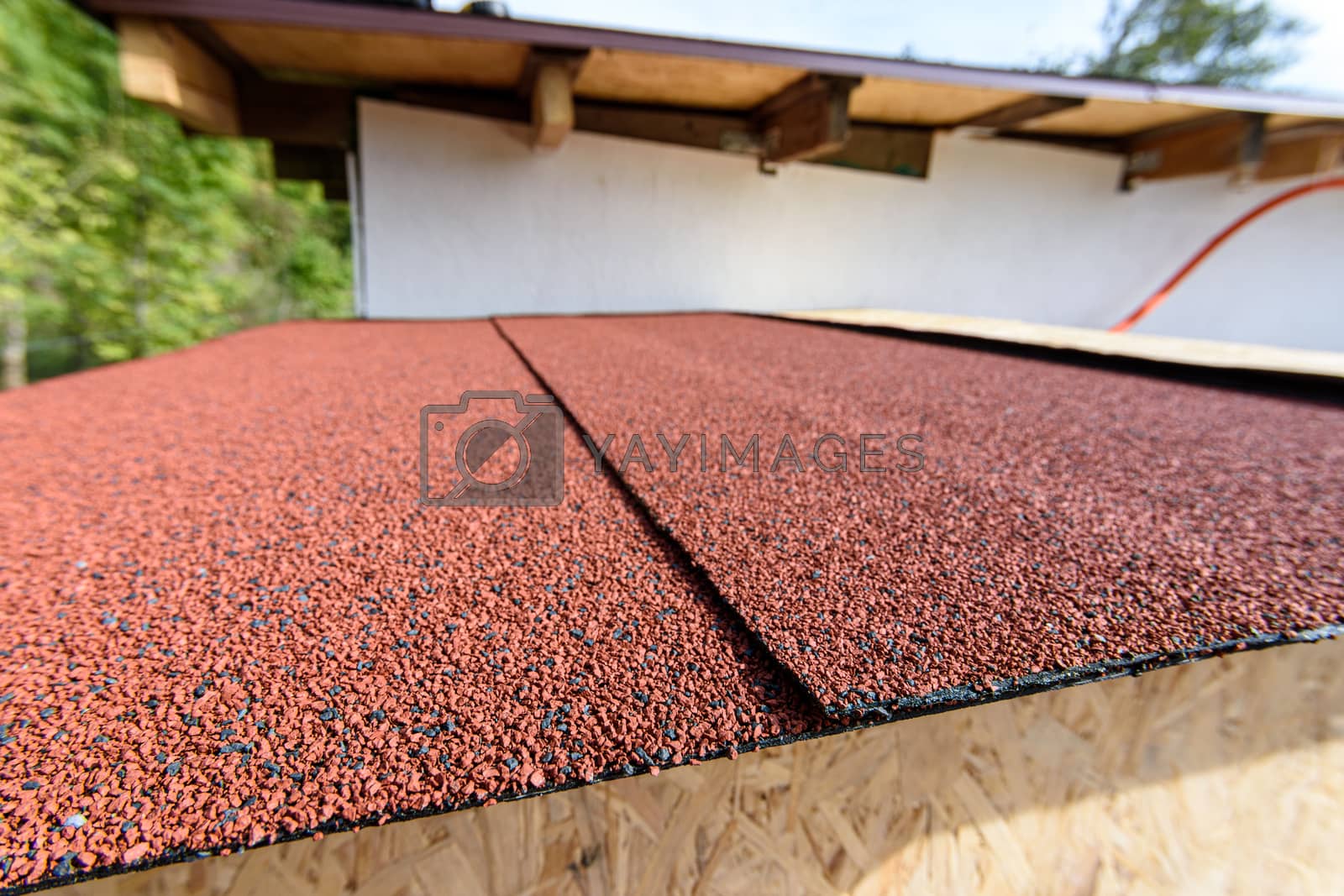 Royalty free image of The roof of a small house is covered with a roof - soft bitumen roll tiles by Madhourse