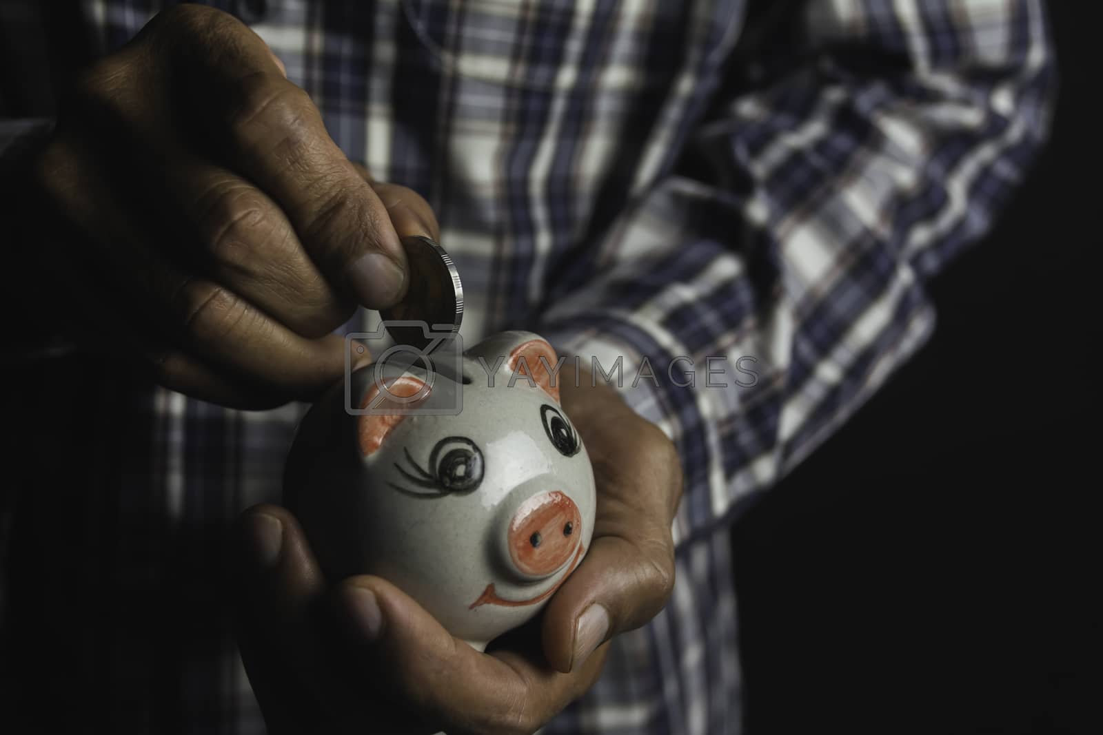 Royalty free image of Saving money concept and hand putting money coin into piggy bank by kirisa99
