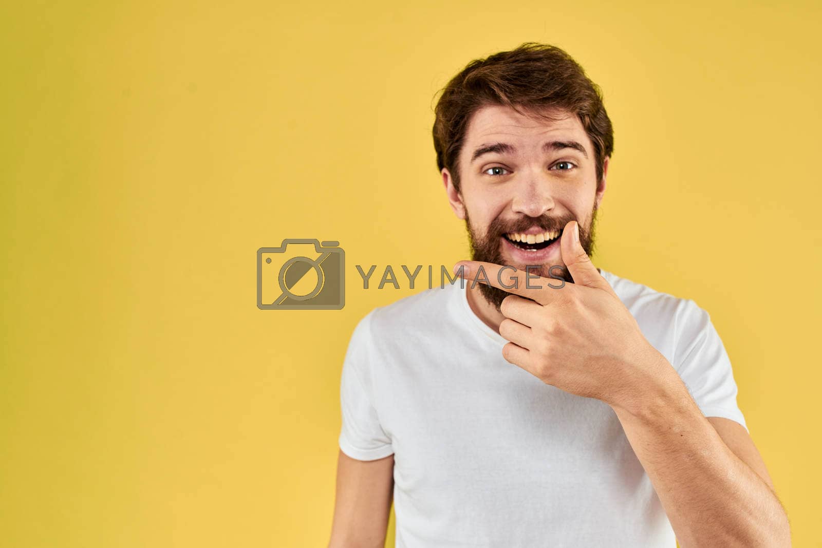 Royalty free image of Bearded man emotions fun gesture with hands white t-shirt close-up yellow background by SHOTPRIME
