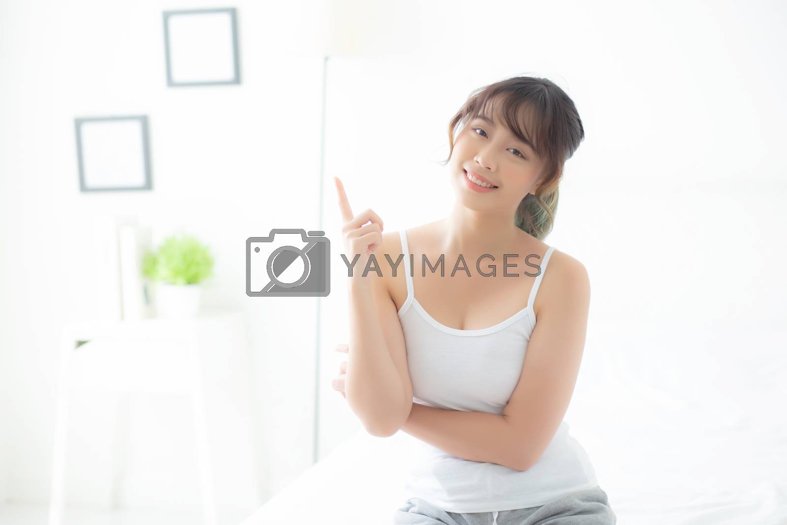 Beautiful portrait young asian woman smiling healthy and wellness at room, beauty asia girl having idea presenting and pointing something skin care and makeup cosmetic, lifestyle concept.