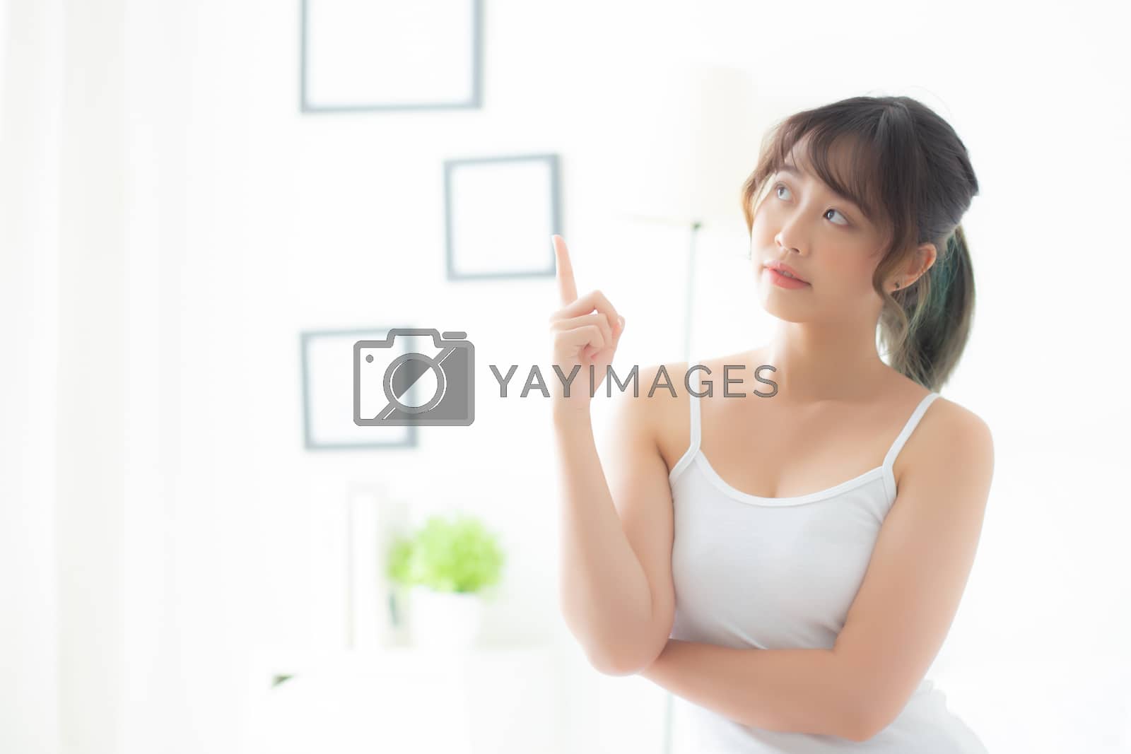 Beautiful portrait young asian woman smiling healthy and wellness at room, beauty asia girl having idea presenting and pointing something skin care and makeup cosmetic, lifestyle concept.