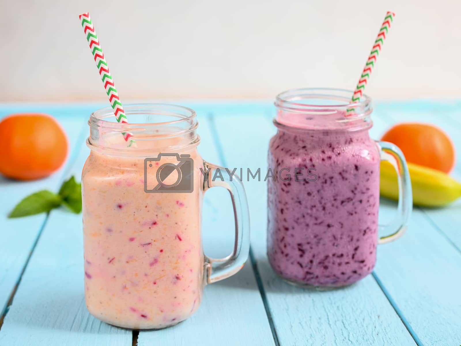 Royalty free image of Blueberry smoothie with mint in mason jar with straw against a wood background by sashokddt