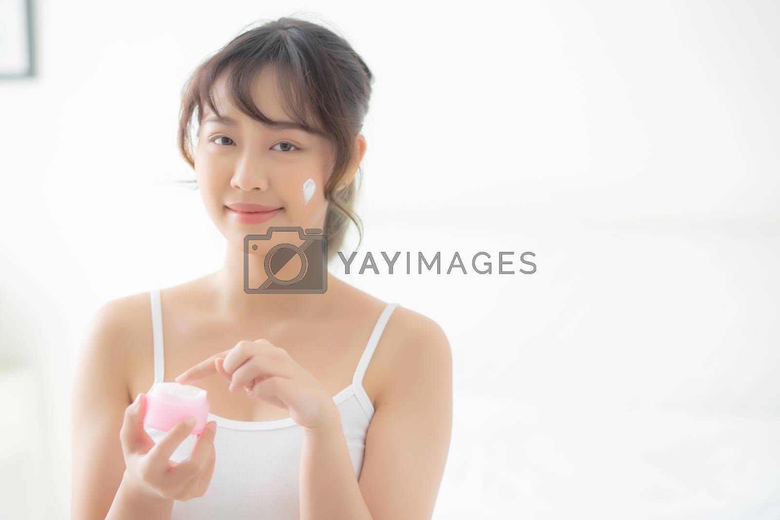 Royalty free image of beautiful young asian woman happy applying cream or lotion with  by nnudoo