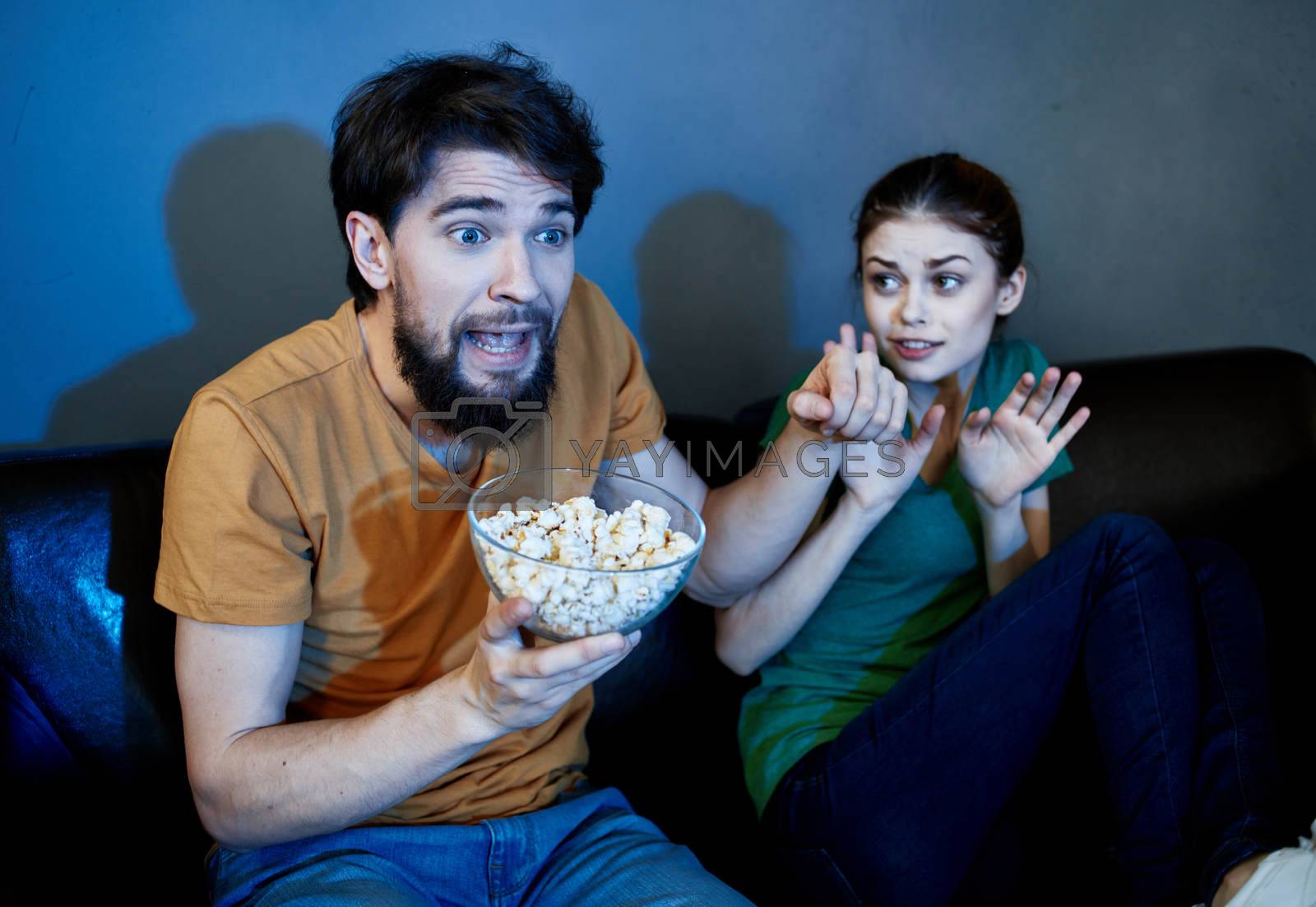 Royalty free image of Friends man and woman watching TV on the couch and popcorn in a plate by SHOTPRIME