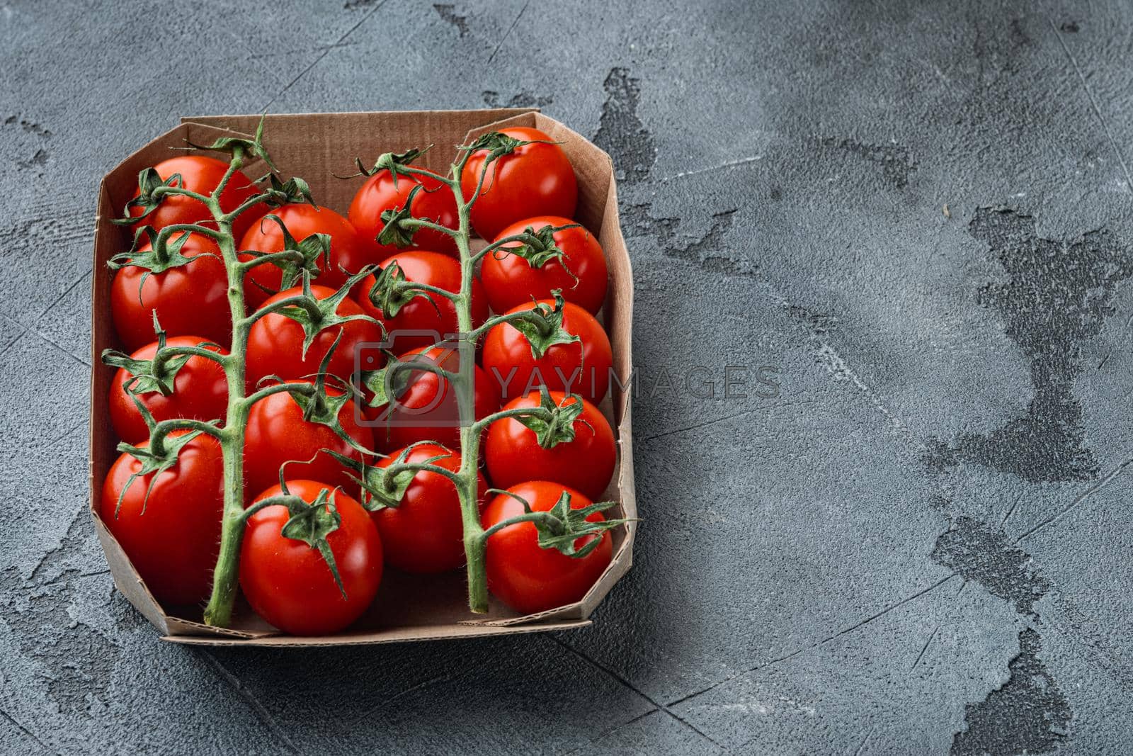 Royalty free image of Ripe cherry tomatoe in tray, on gray background with copy space for text by Ilianesolenyi