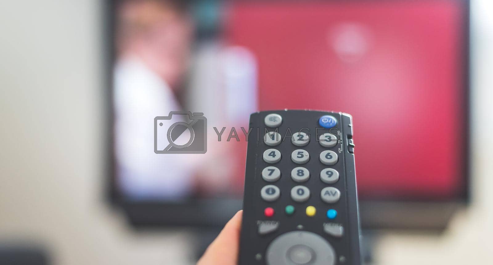 Royalty free image of Male hand is holding TV remote control, streaming on a smart TV. by Daxenbichler