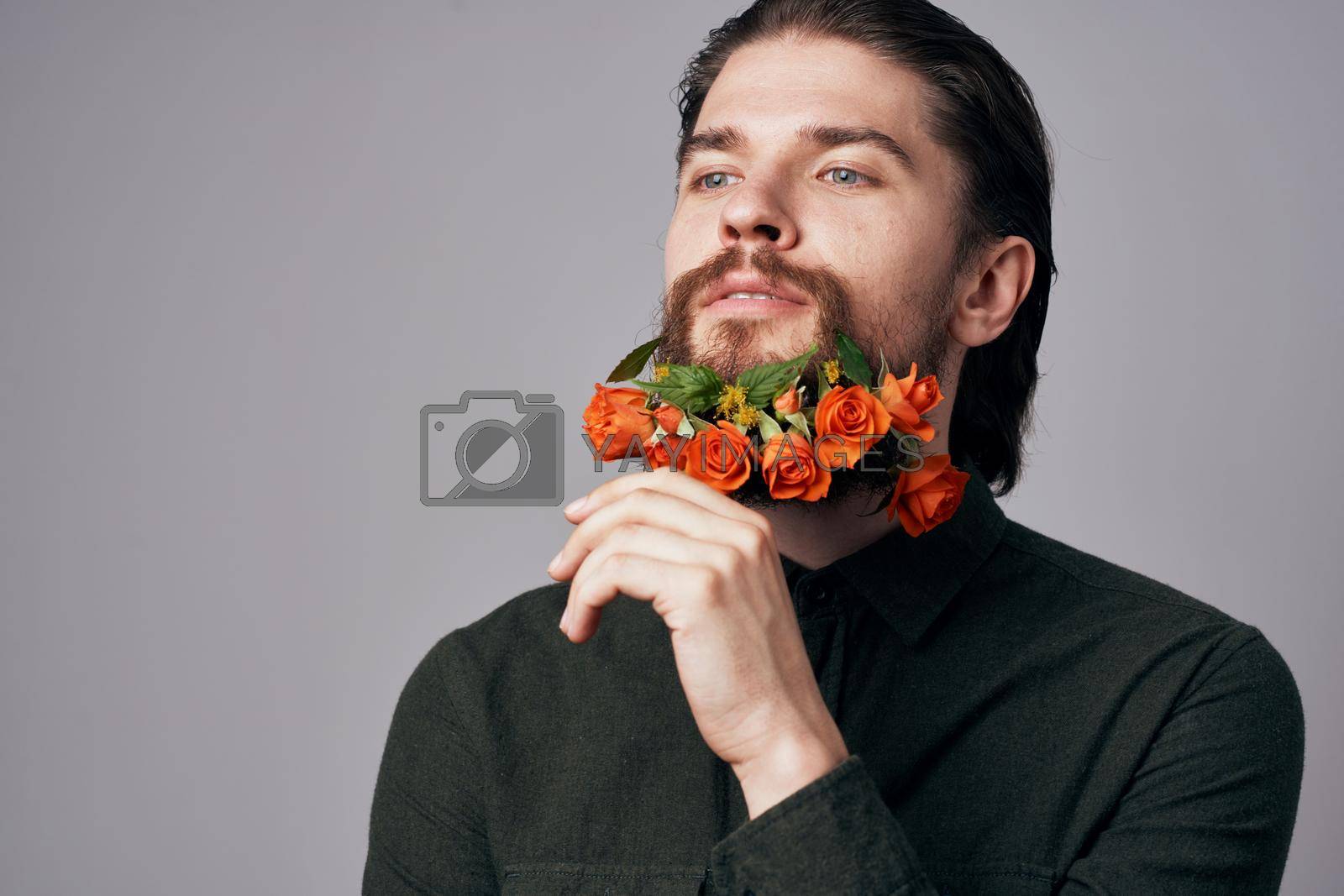 Cute elegant man in a black shirt flowers in a beard decoration romance gray background. High quality photo