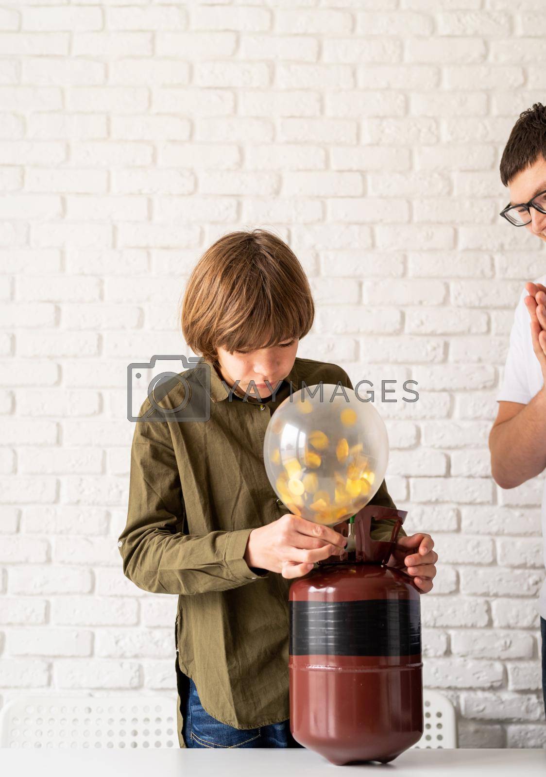 Royalty free image of boy blowing up a balloon with helium by Desperada