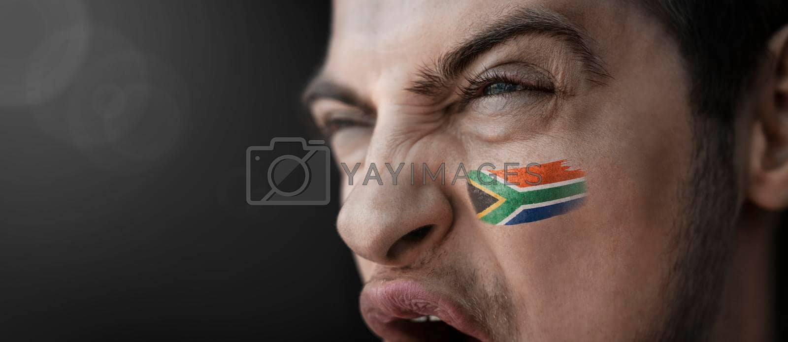 Royalty free image of A screaming man with the image of the South Africa national flag on his face by butenkow