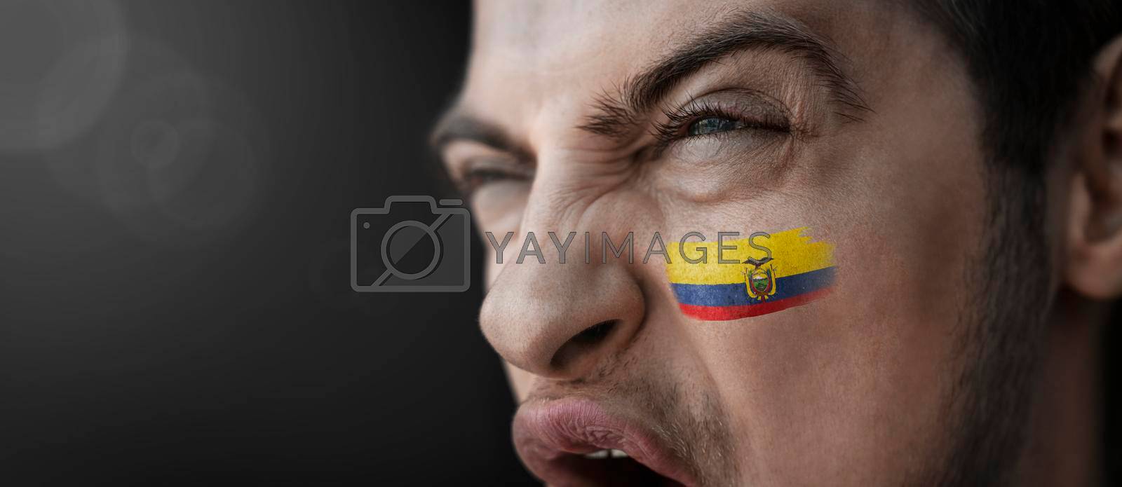 Royalty free image of A screaming man with the image of the Ecuador national flag on his face by butenkow