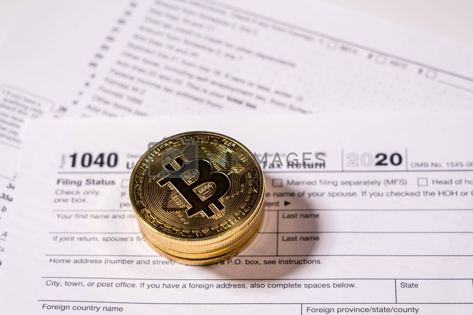 Royalty free image of Form 1040 with bitcoin coins for reporting cyber currency gains by steheap