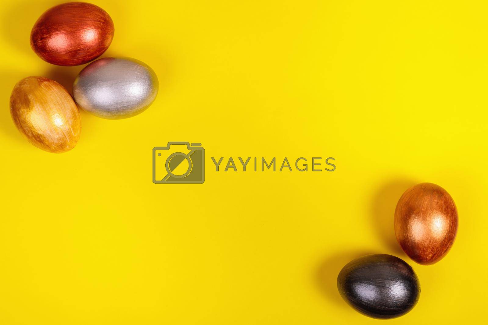 Royalty free image of Multi-colored eggs on a uniform yellow background with place for text. by Yurich32