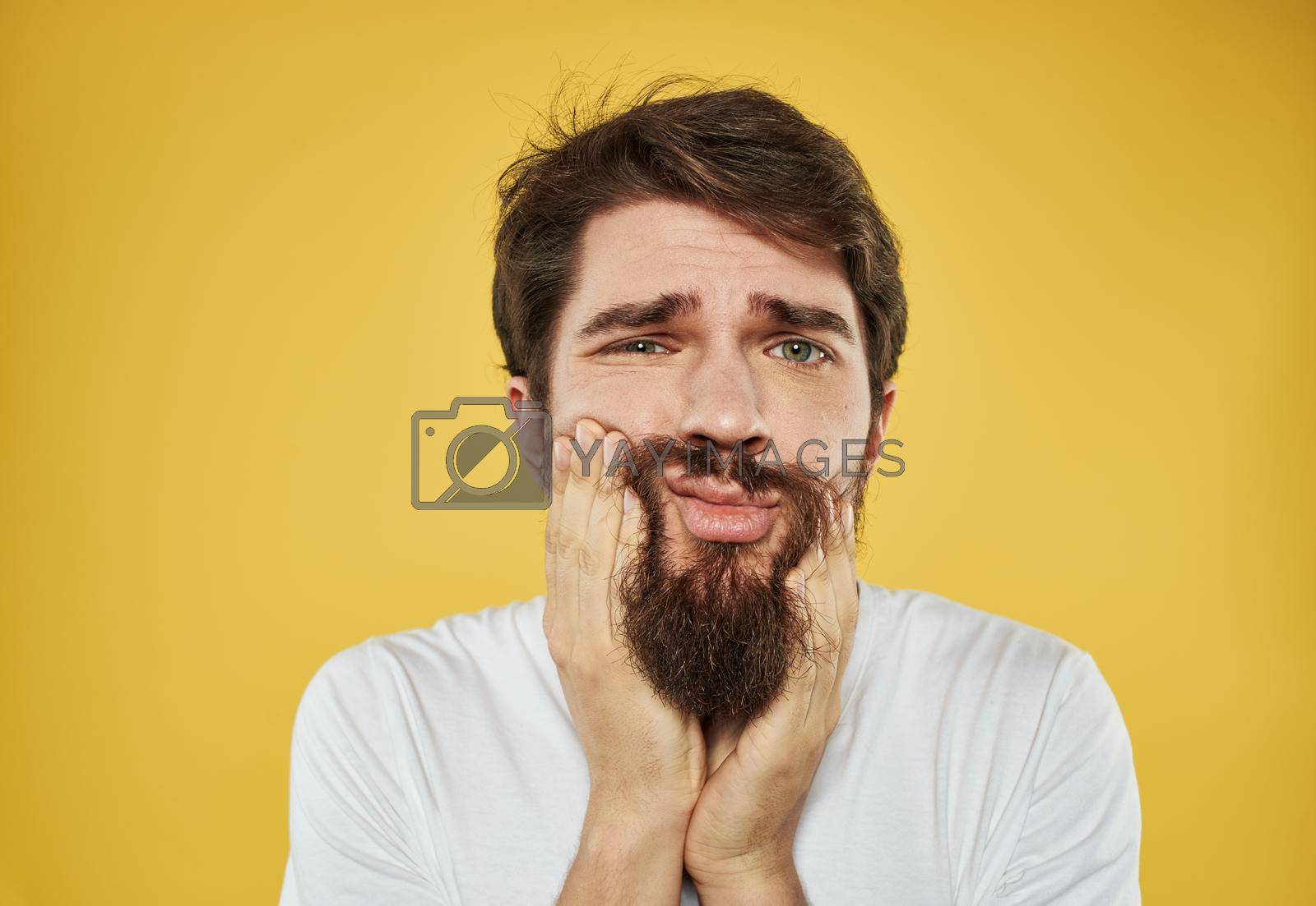 Royalty free image of Frightened sad man touching face with hands on yellow background cropped view by SHOTPRIME