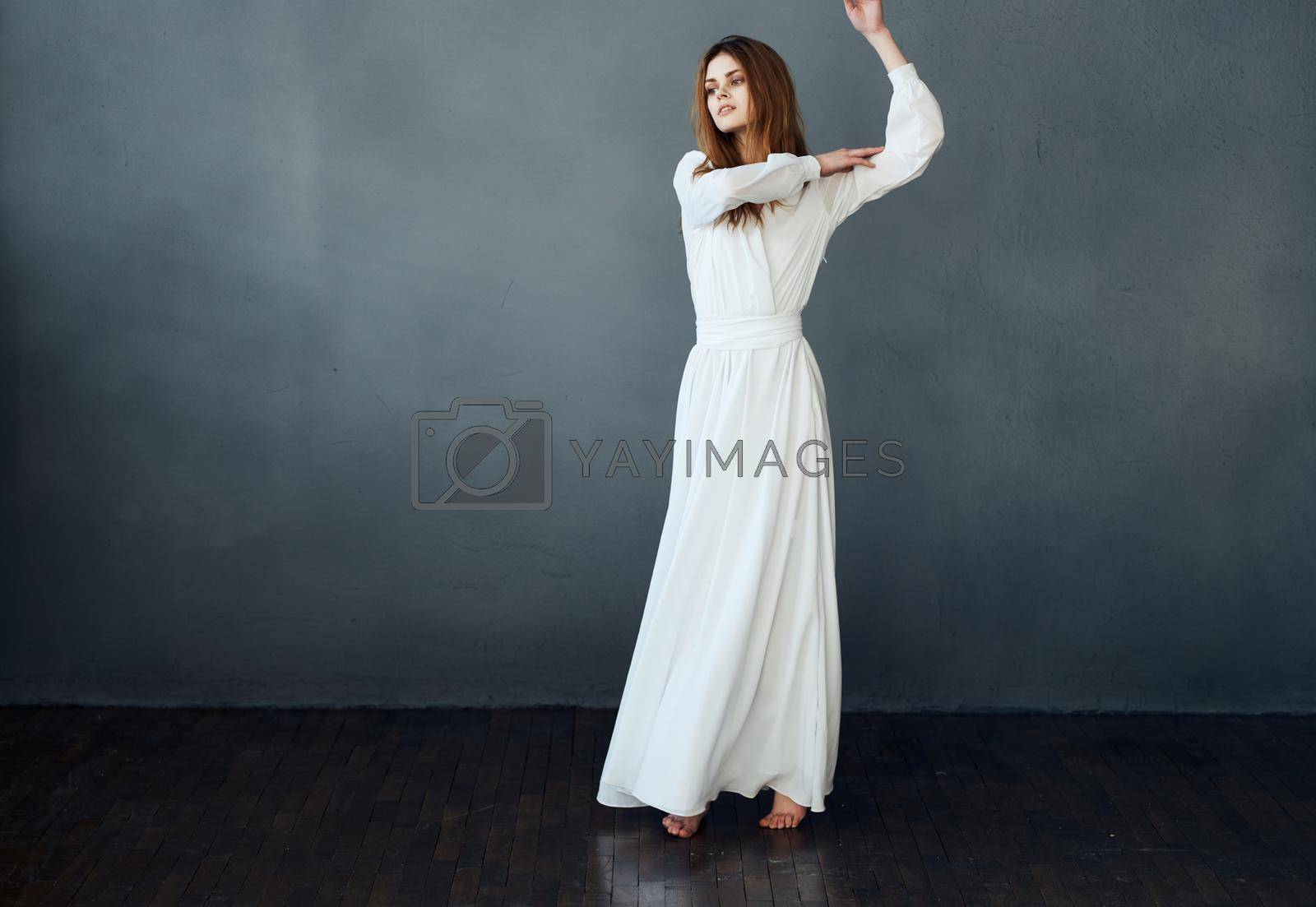 Woman in white dress on gray background red hair model romance . High quality photo
