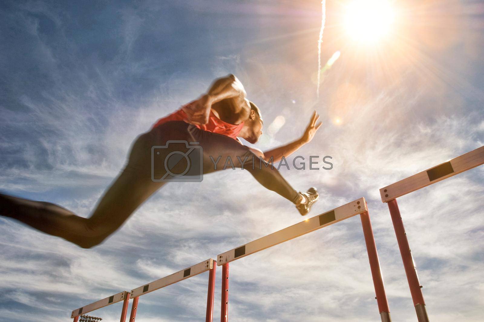 Royalty free image of Runner jumping over running hurdle, low angle view by moodboard