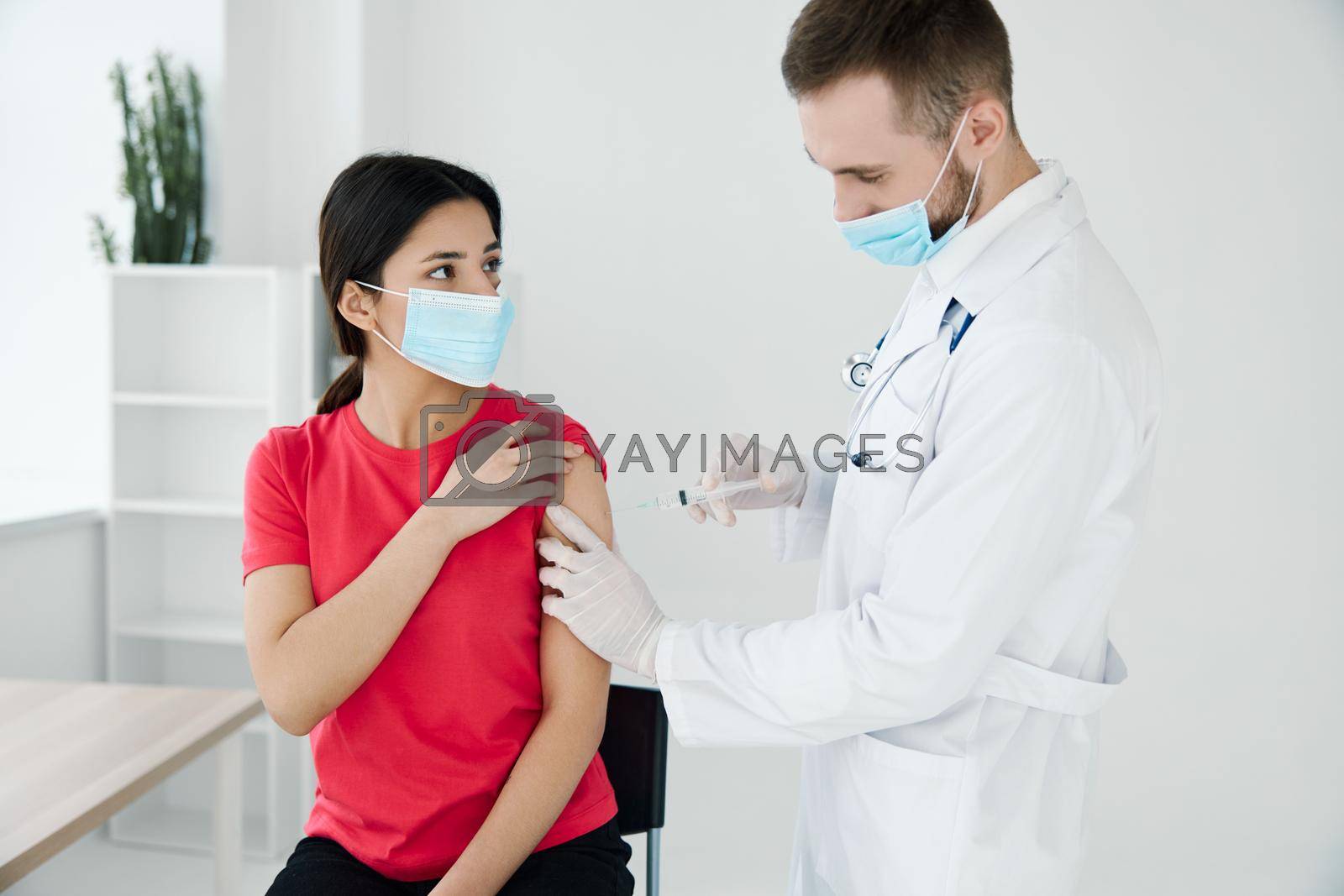 Royalty free image of male doctor in a medical mask injecting a female patient in the shoulder covid vaccination by SHOTPRIME