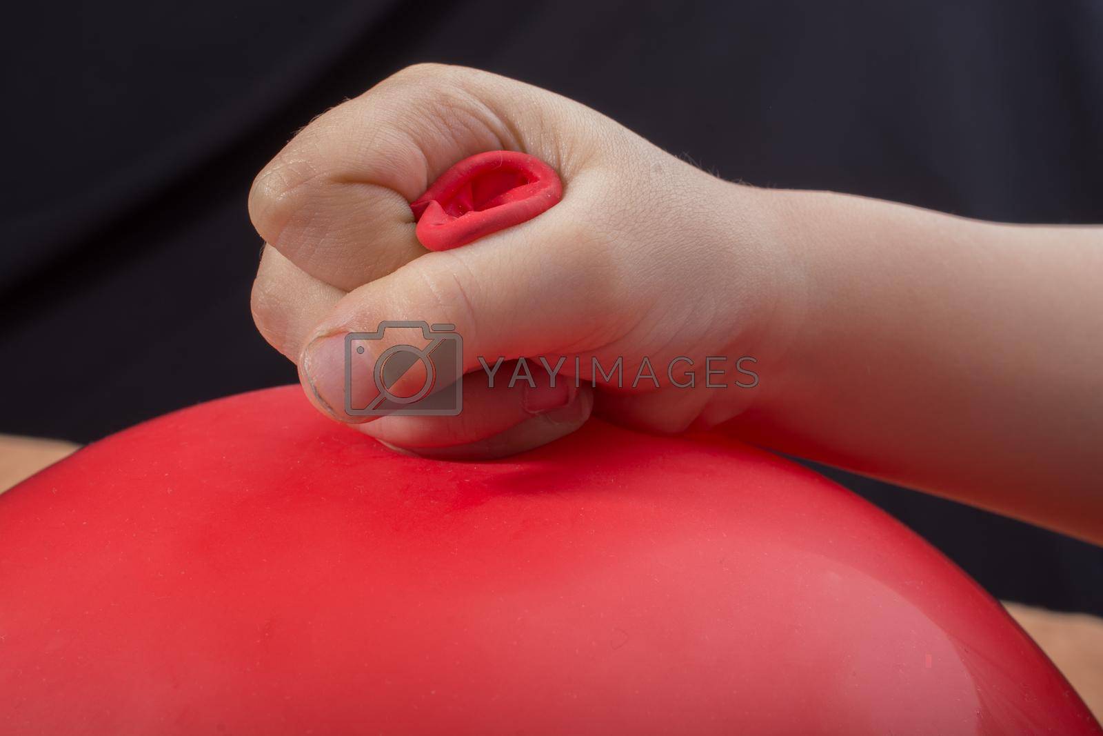 Toddlers hand holding a red balloon in hand