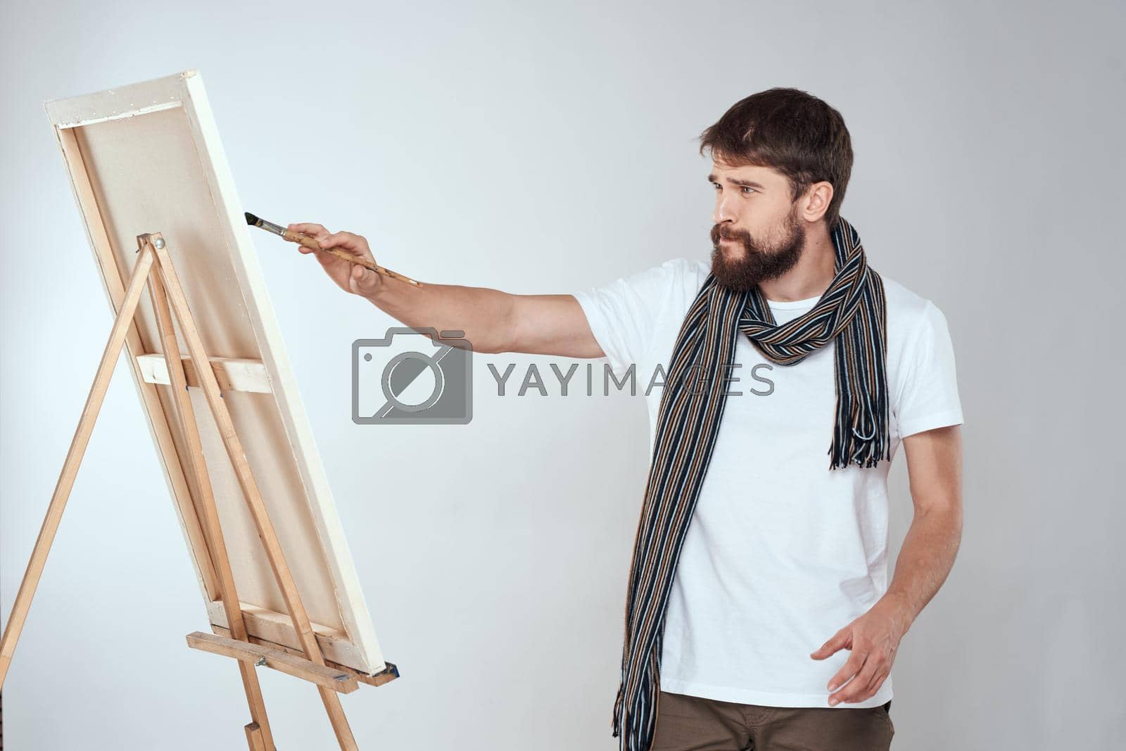 male artist painting on easel art lifestyle light background. High quality photo