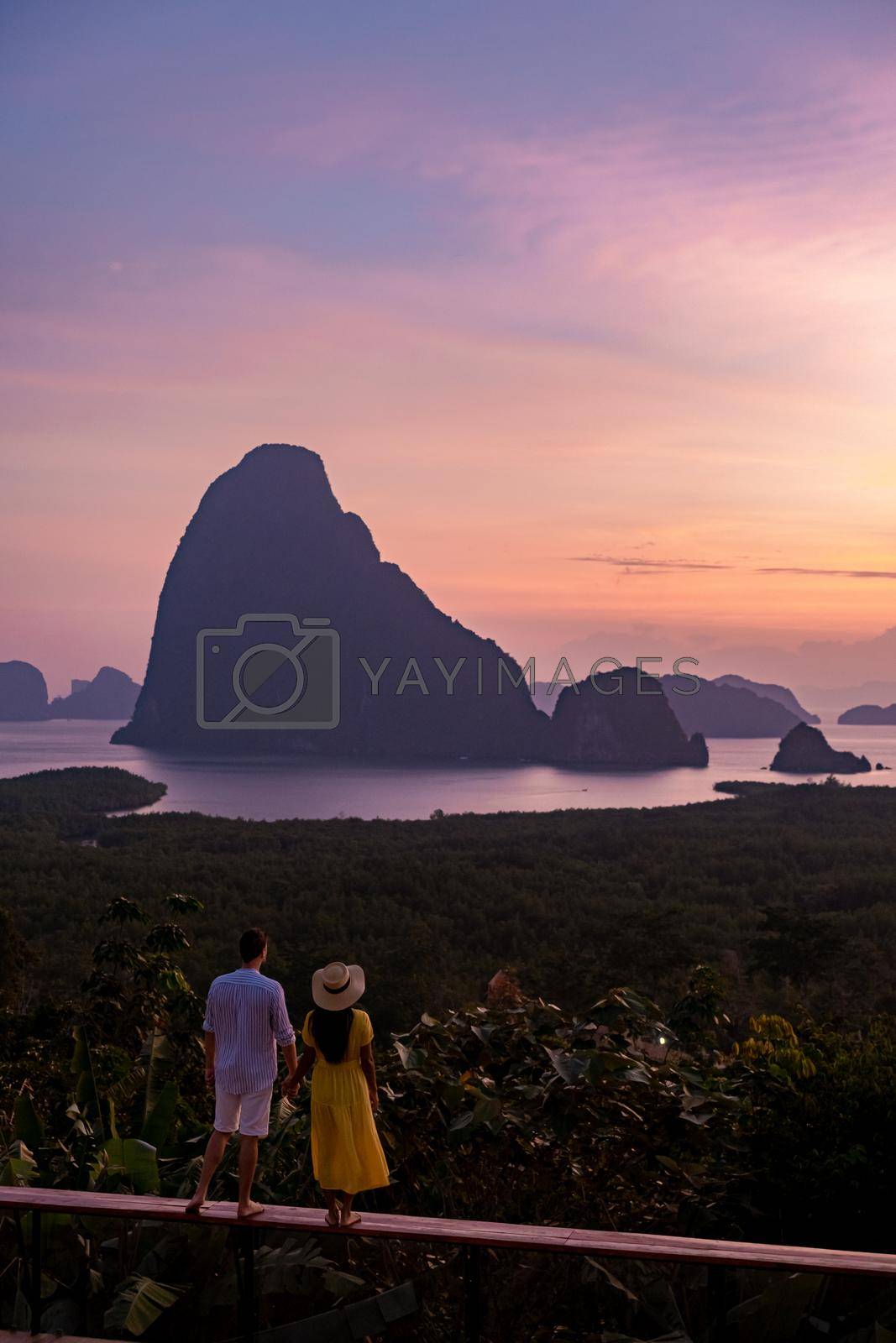 Royalty free image of couple men and woman mid age watching sunrise in Phangnga bay Thailand, Phanga bay viewpoint, couple watching sunrise on the edge of a swimming pool, infinity pool look out over Phangnga Bay Thailand by fokkebok