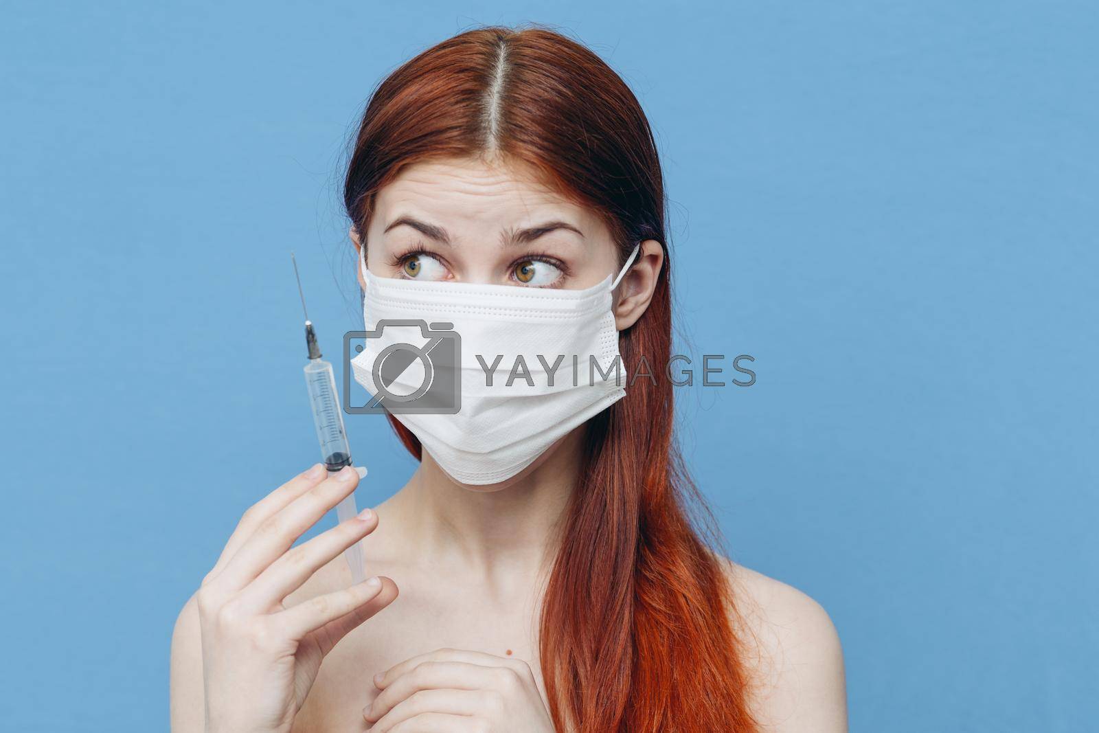 Royalty free image of woman in medical mask holds syringe in hand and bare shoulders botox injection by SHOTPRIME