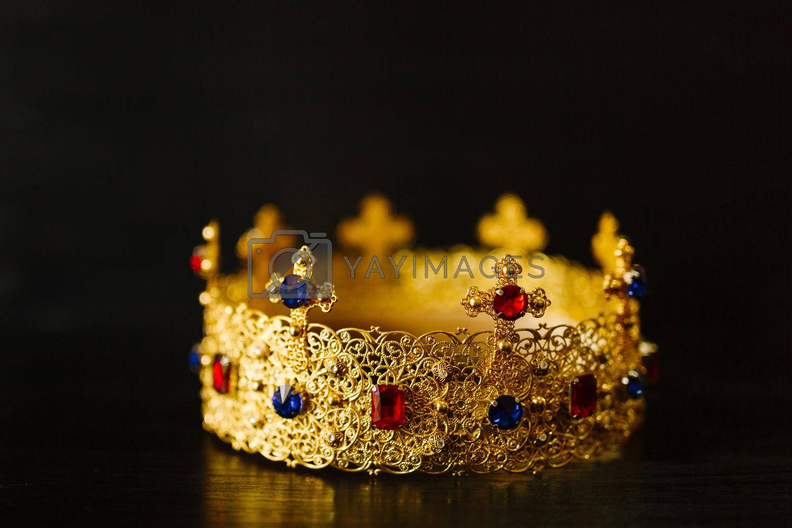 Royalty free image of Golden crown encrusted with blue and red gemstones by Nadtochiy