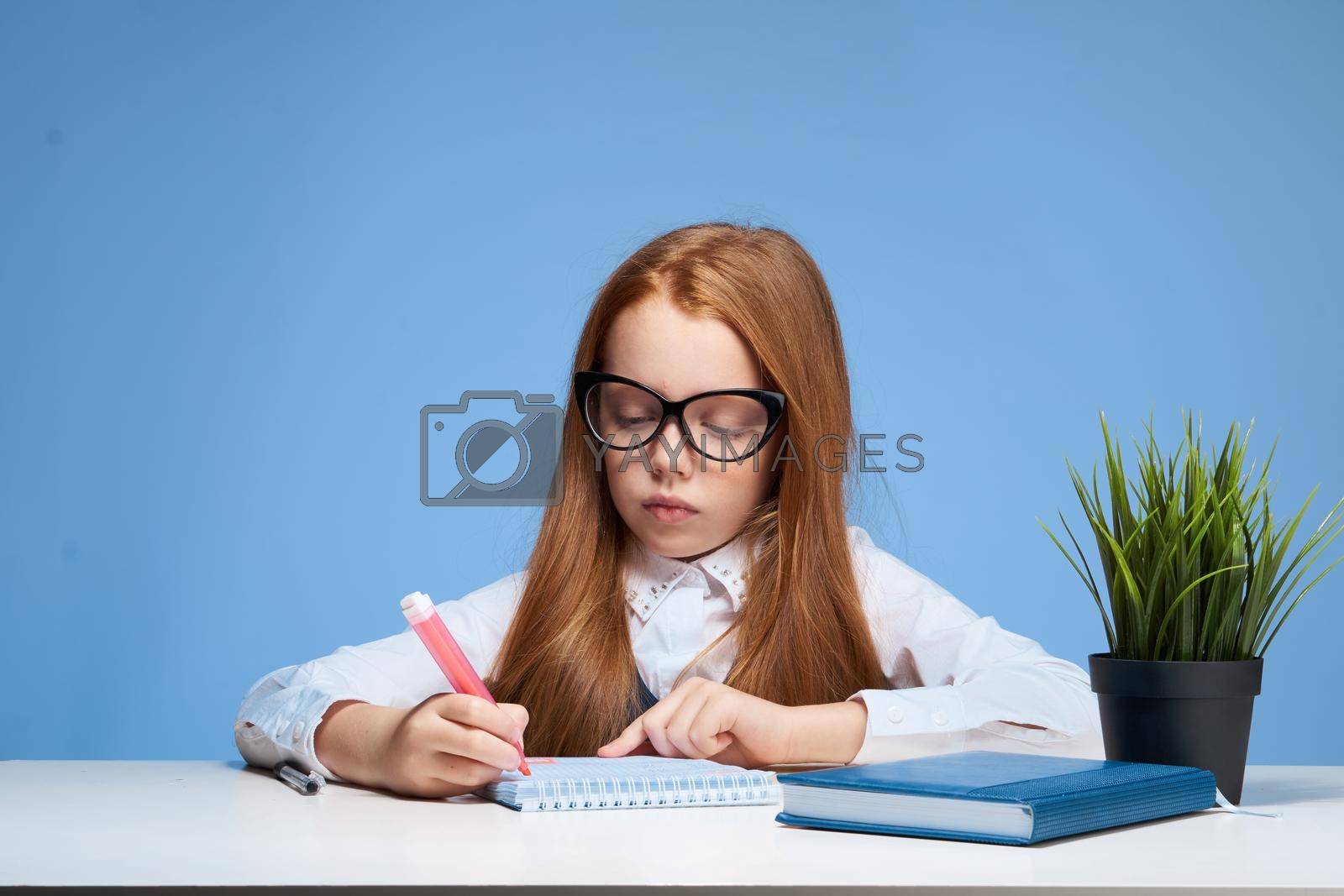 red-haired girl with glasses doing homework at the table school education. High quality photo
