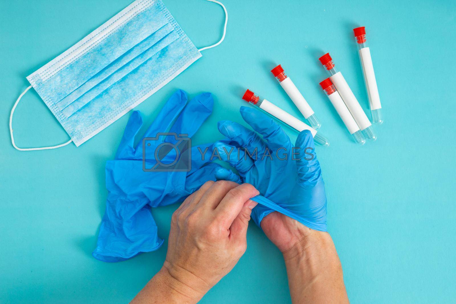 Royalty free image of hands remove glove on blue background. by tehcheesiong