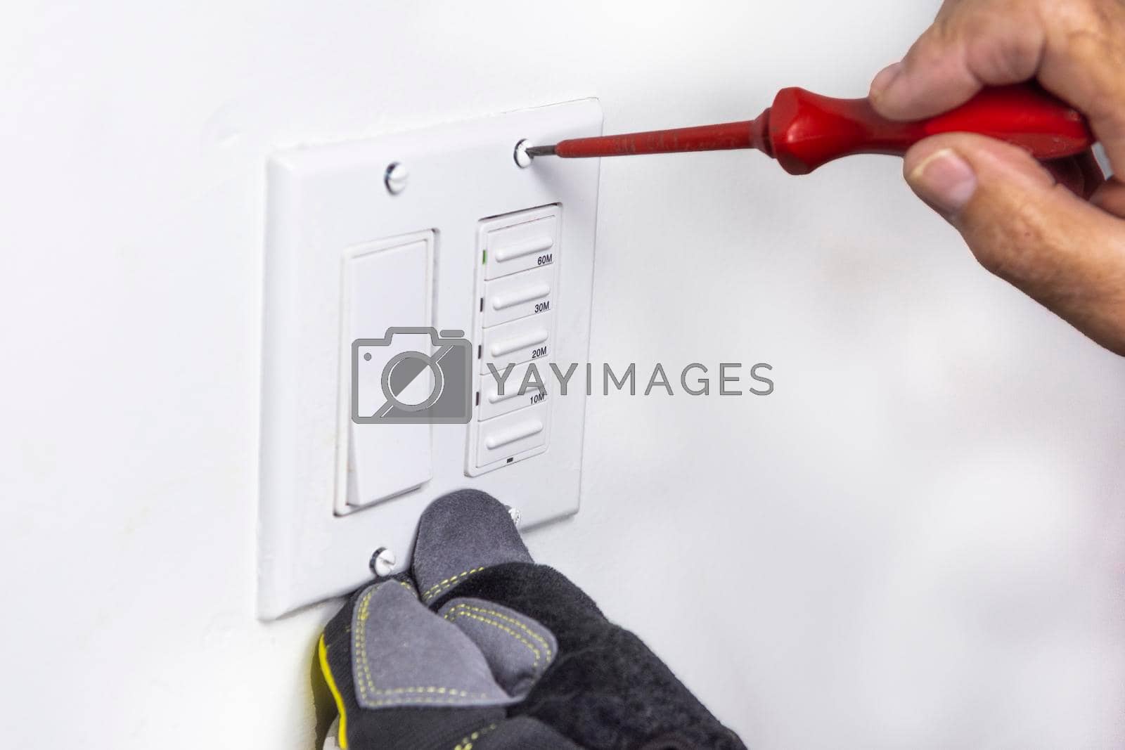 Royalty free image of Electrician tightens the screws that secure the switch cover by ben44