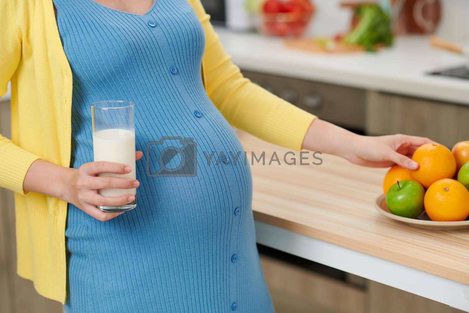 Royalty free image of Young pregnant woman holding glass of milk near table with food in kitchen by makidotvn