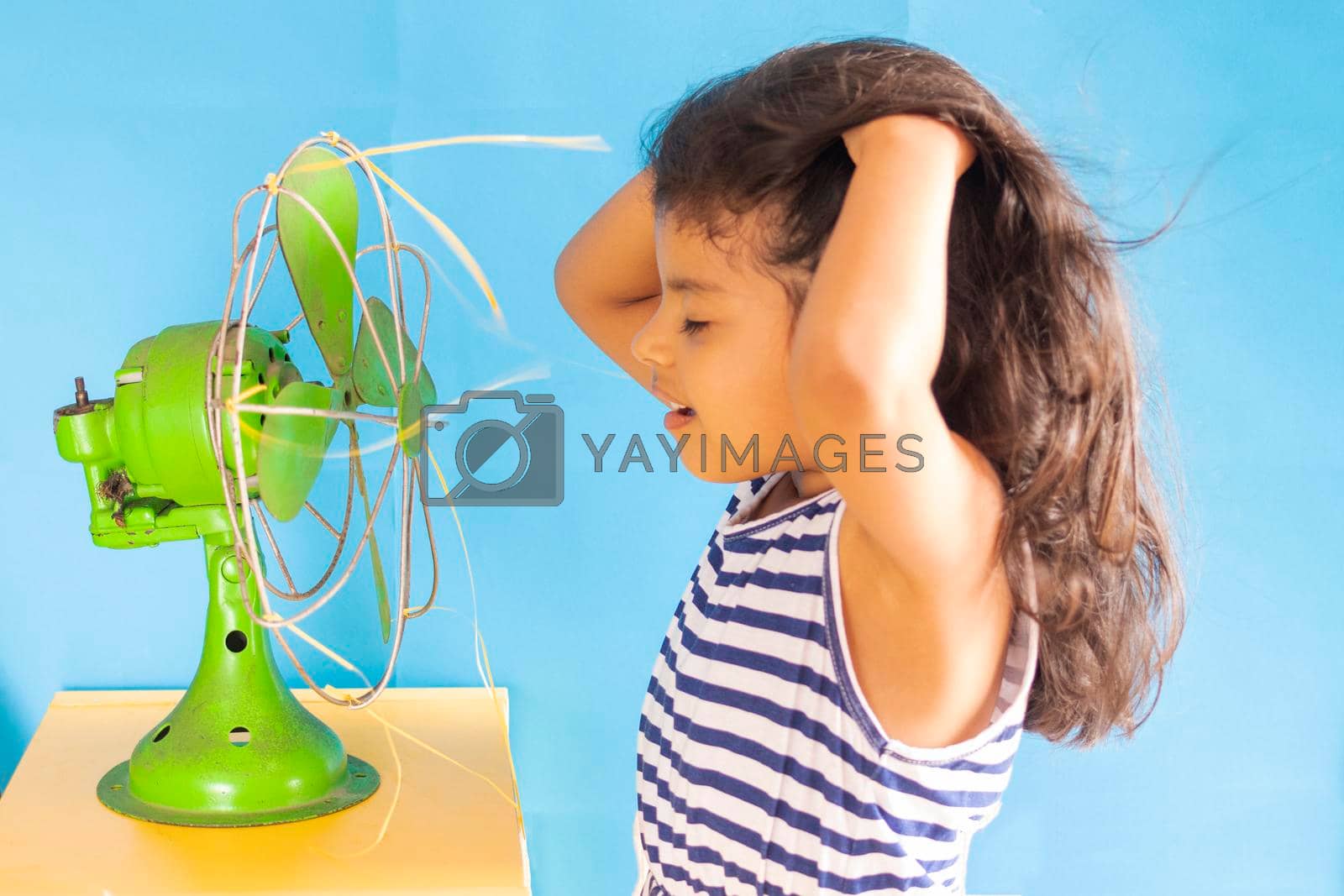 Royalty free image of Beautiful girl, is cooling off the heat with an old green fan by eagg13