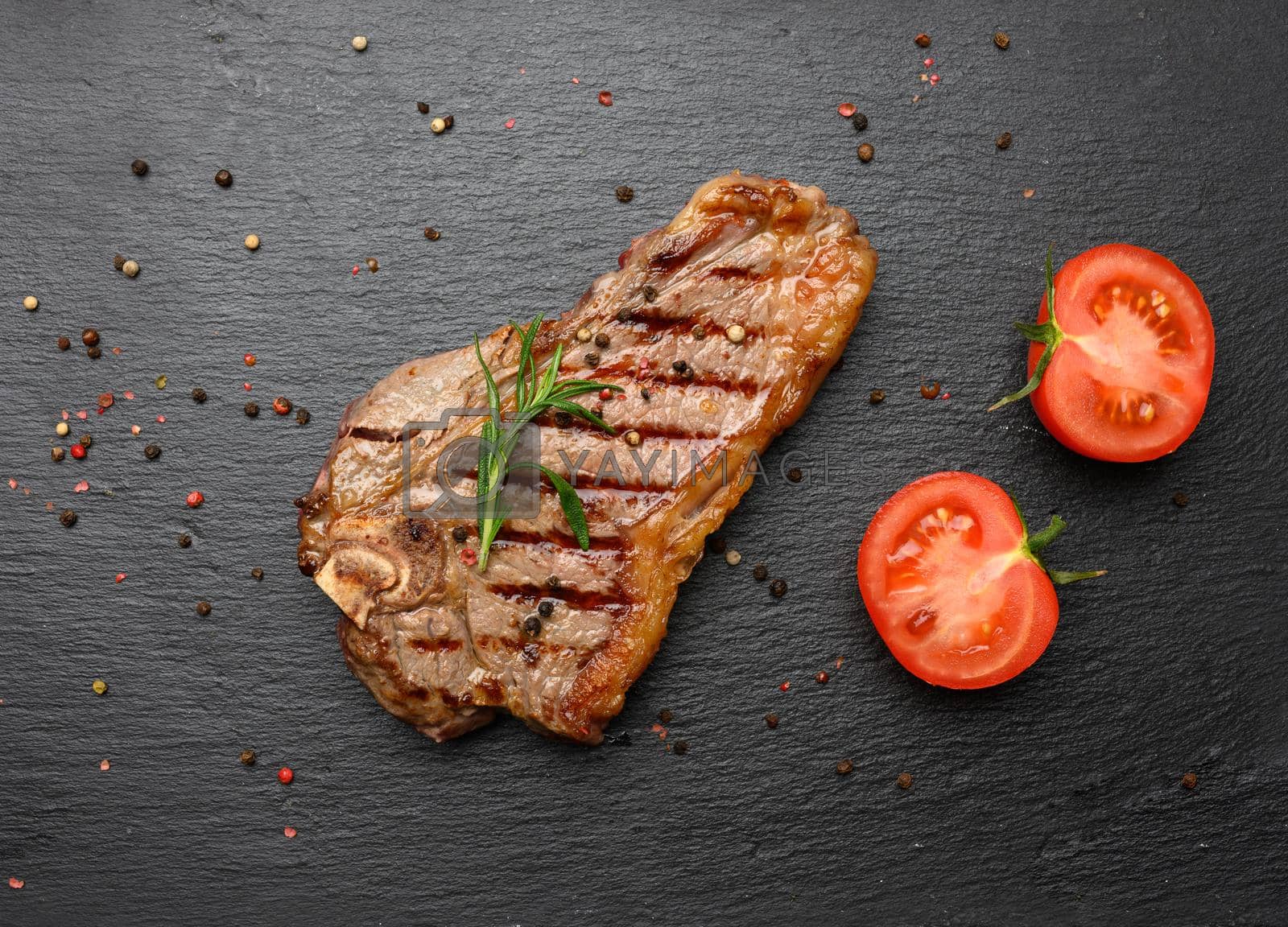 Royalty free image of whole fried New York beef steak on a black board,  striploin doneness rare by ndanko