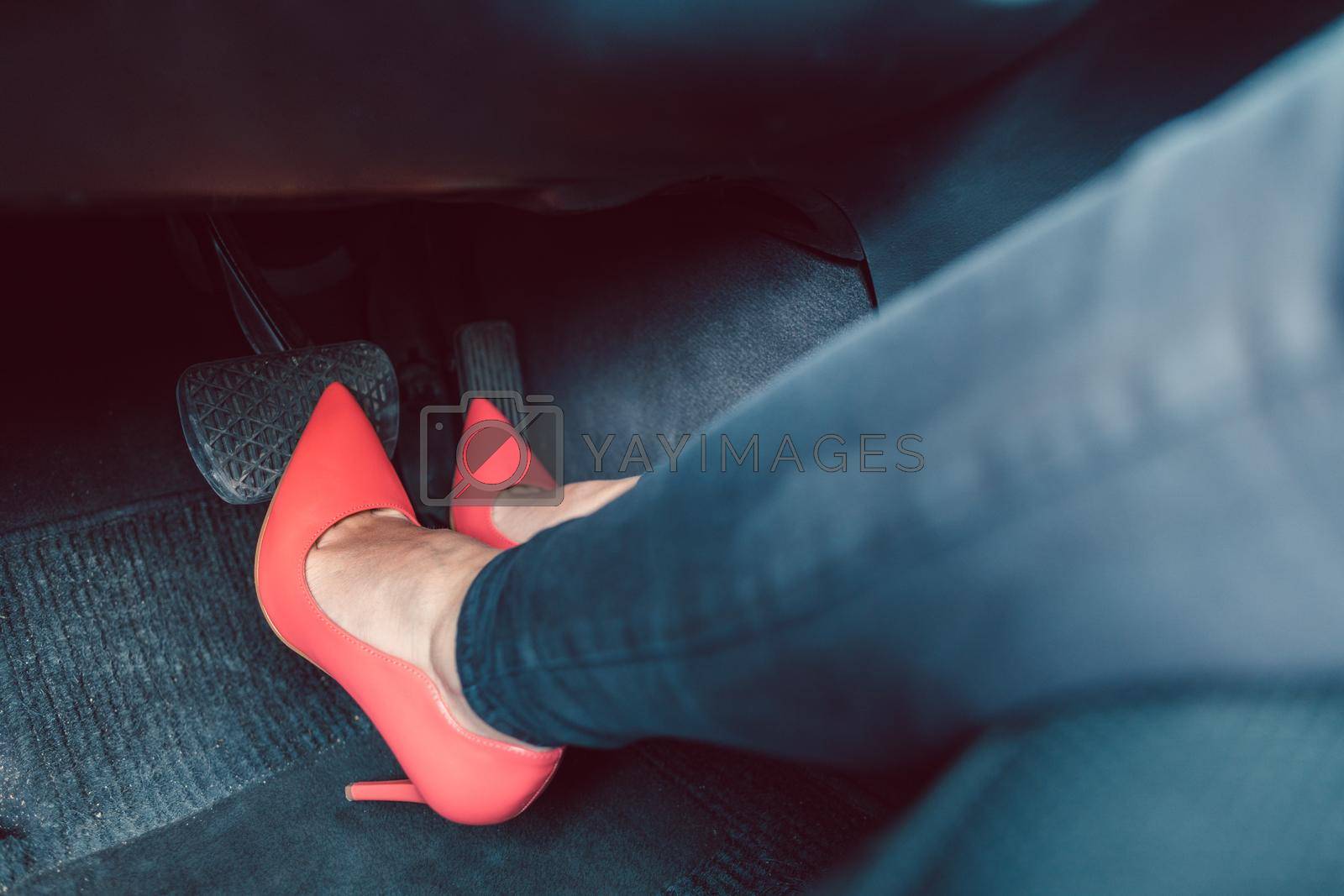 Royalty free image of Woman driving a car in an unsafe manner with high-heel shoes by Kzenon