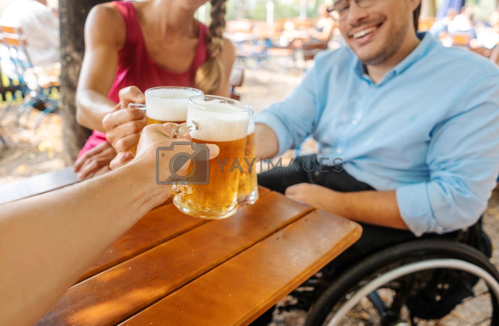 Royalty free image of Friends in beer garden drinking, one man is in a wheelchair by Kzenon
