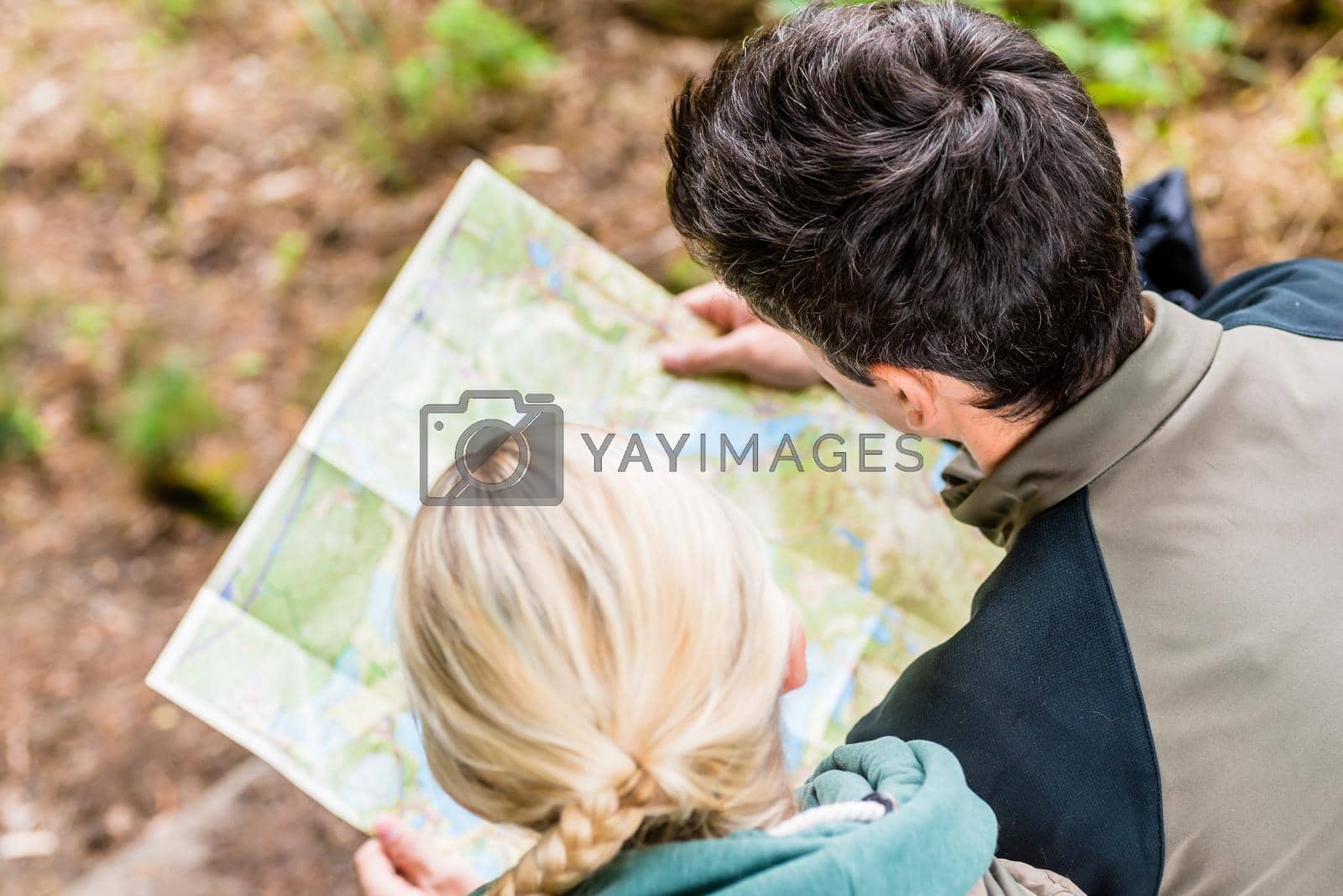 Royalty free image of Hikers bending over trail map by Kzenon