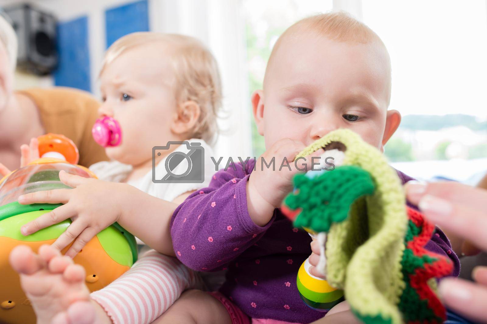 Royalty free image of Babies with pacifier in toddler group playing with toys by Kzenon