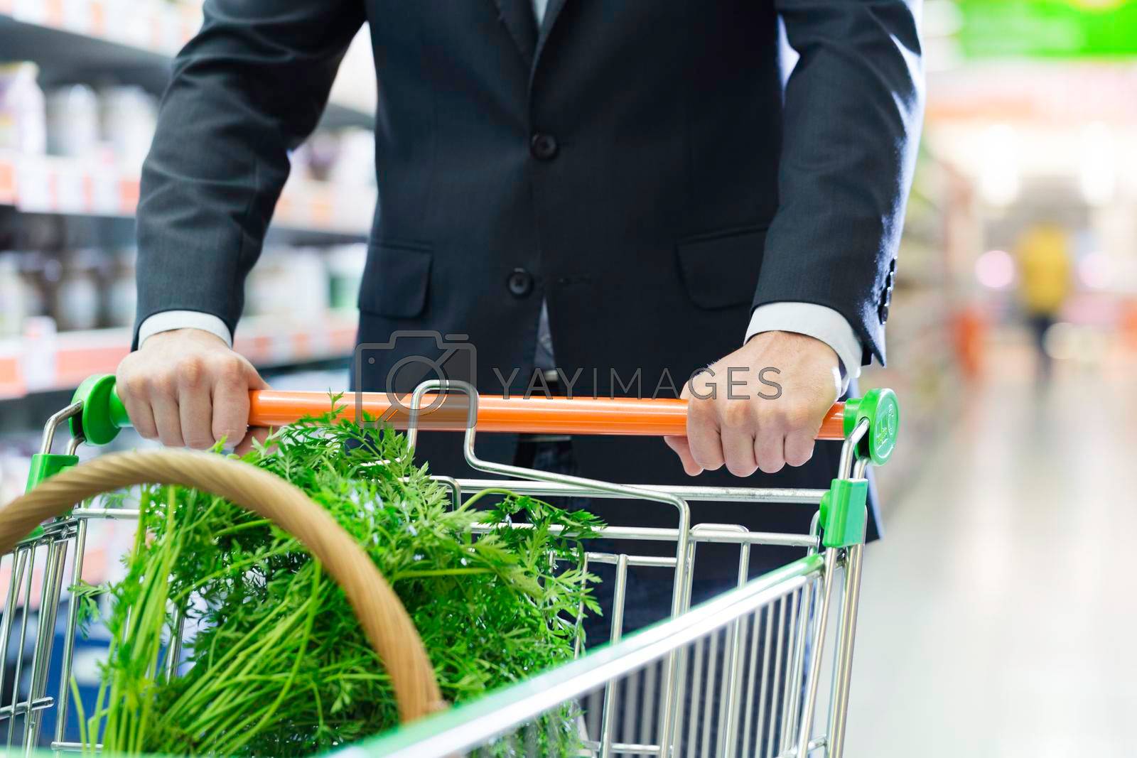 Royalty free image of man with shopping cart in supermarket by Kzenon
