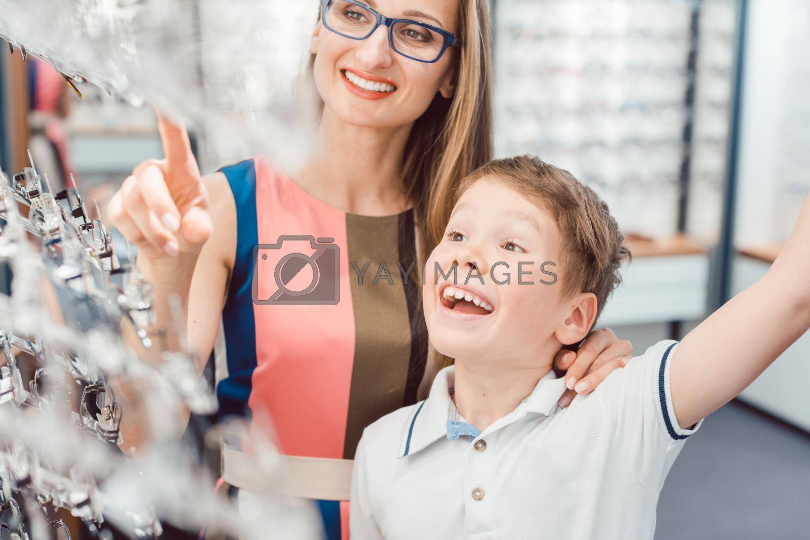 Royalty free image of Mother and son both liking the eyeglasses offered in optician shop by Kzenon