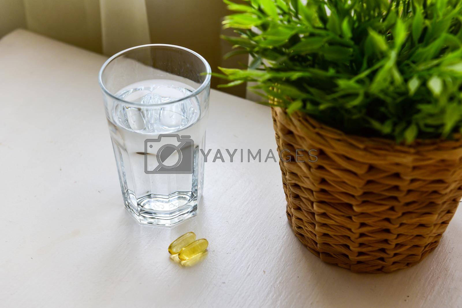 Royalty free image of Omega-3, spirulina, chlorophyll capsules and glass of water on white wooden table. Dietary supplements, biologically active additives. vitamin pills. Health support by karpovkottt