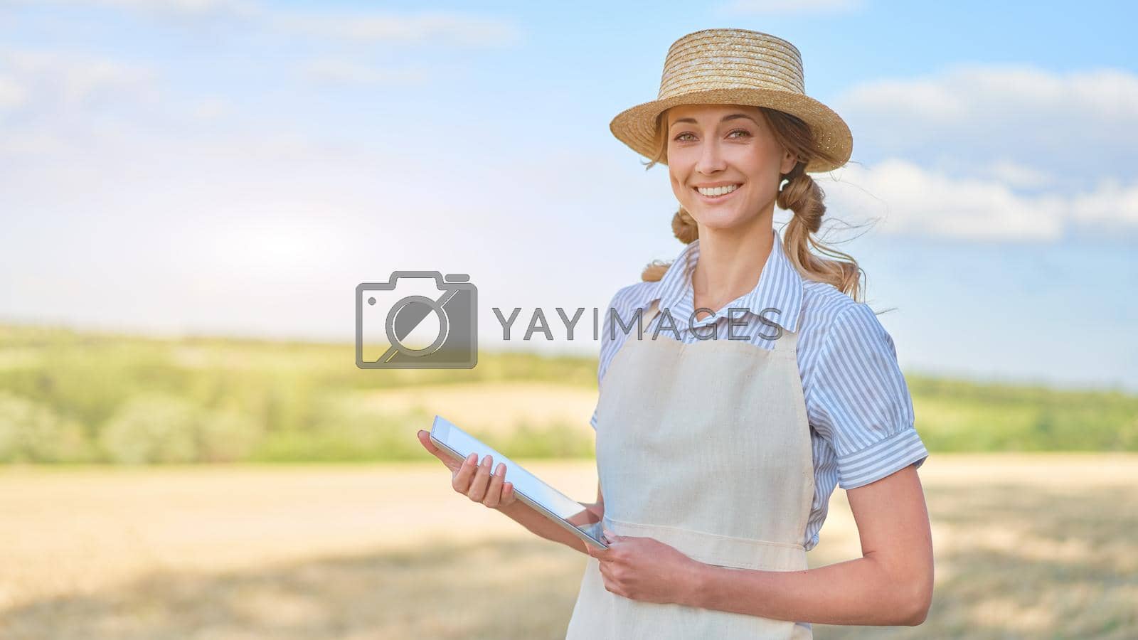 Royalty free image of Woman farmer straw hat smart farming standing farmland smiling using digital tablet Female agronomist specialist research monitoring analysis data agribusiness by andreonegin