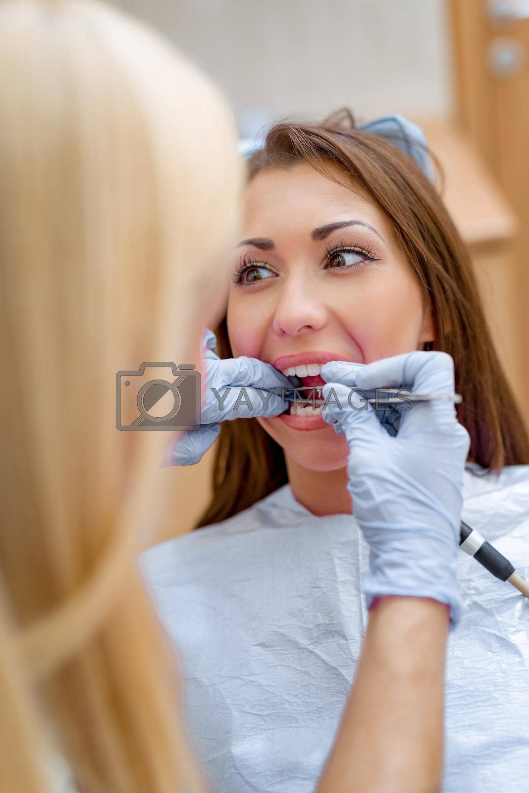 Beautiful young smiling woman at visit in the dentist office and female dentist checkup her teeth. 