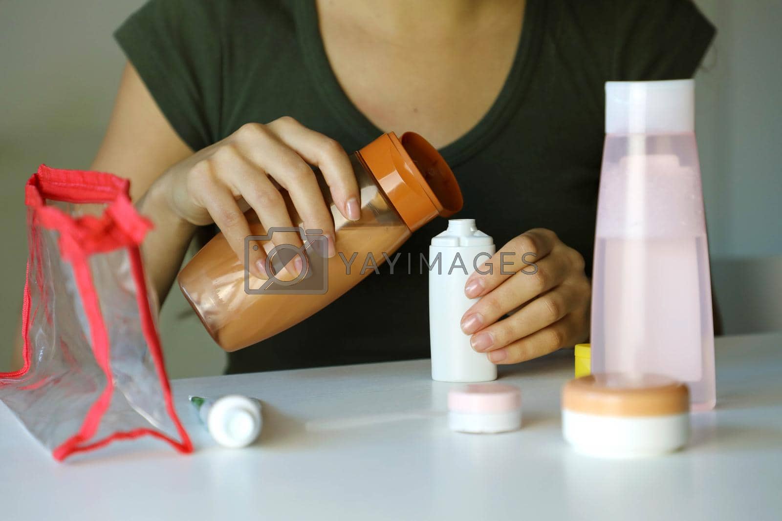 Travel kit for transporting cosmetics on airplane. Woman poured cosmetics liquid into small bottles preparing travel kit for transporting on airplane.