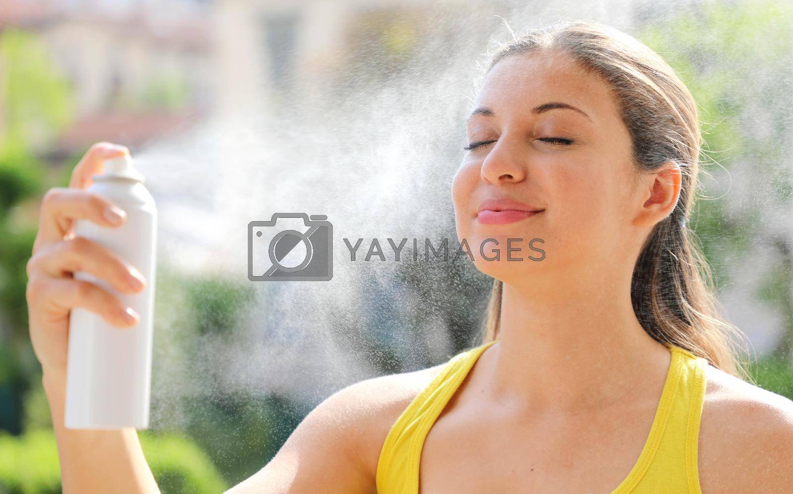 Royalty free image of Young woman spraying Thermal Water on her face outside. Thermal water used for skin care, fix makeup, help skin irritation, redness and insect bites. by sergio_monti