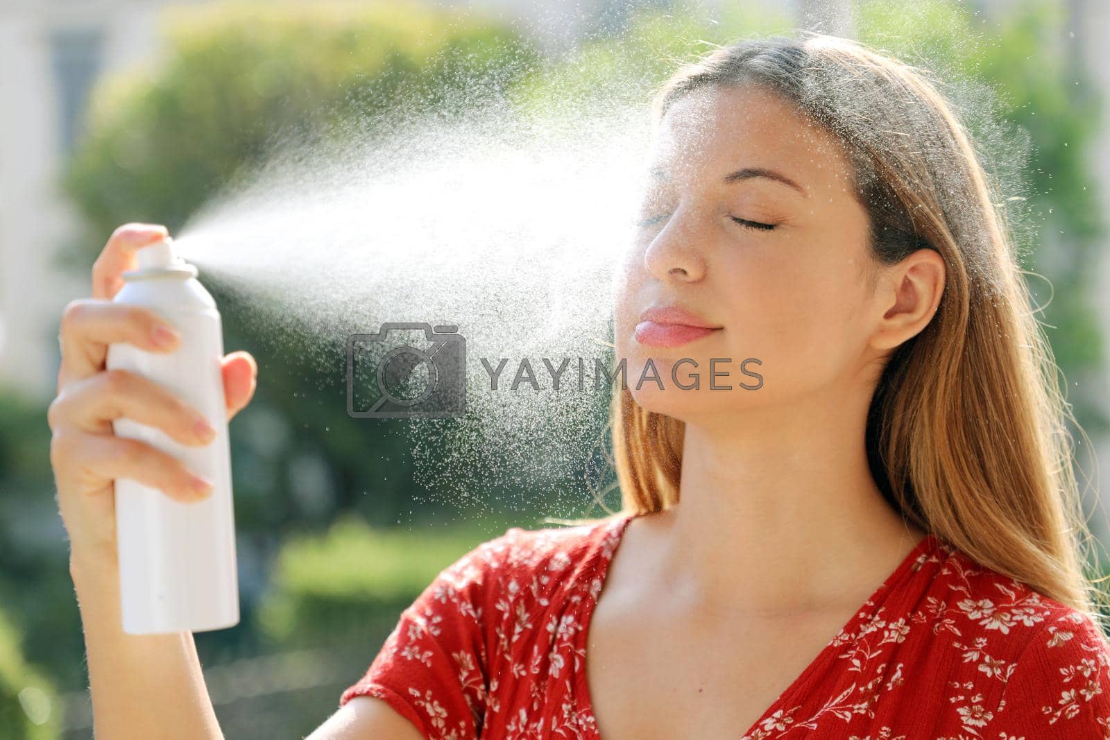 Royalty free image of Young woman applying thermal water on face outdoor. Thermal water used for skin care, fix makeup, help skin irritation, redness and insect bites. by sergio_monti