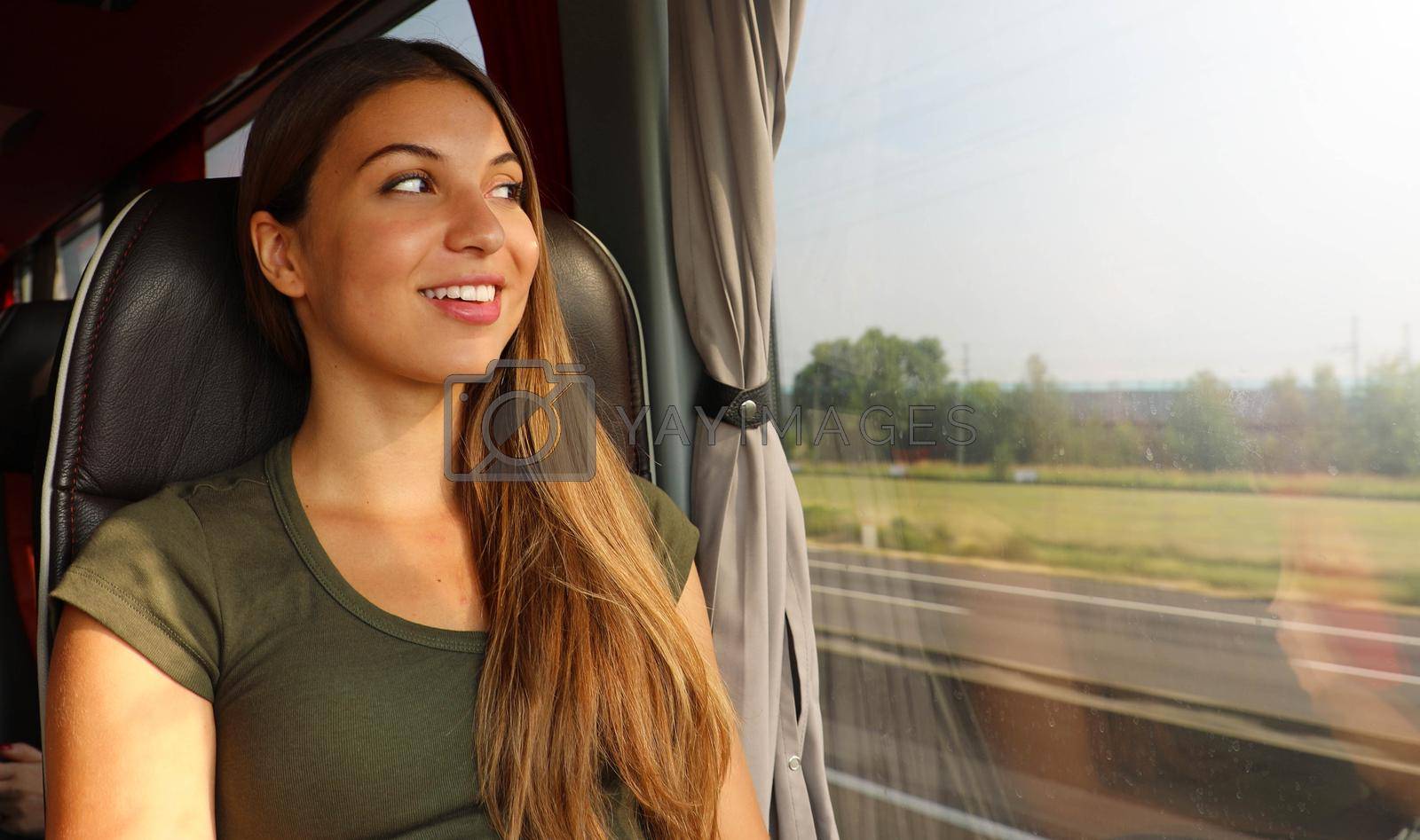 Train or bus travel. Beautiful smiling woman looking through the window during the trip on public transportation.