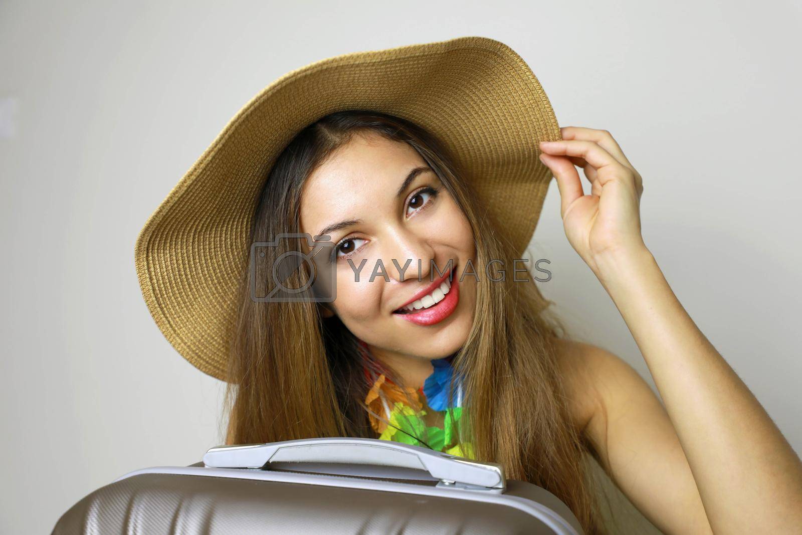 Portrait of young woman wearing straw hat standing with travel bag
