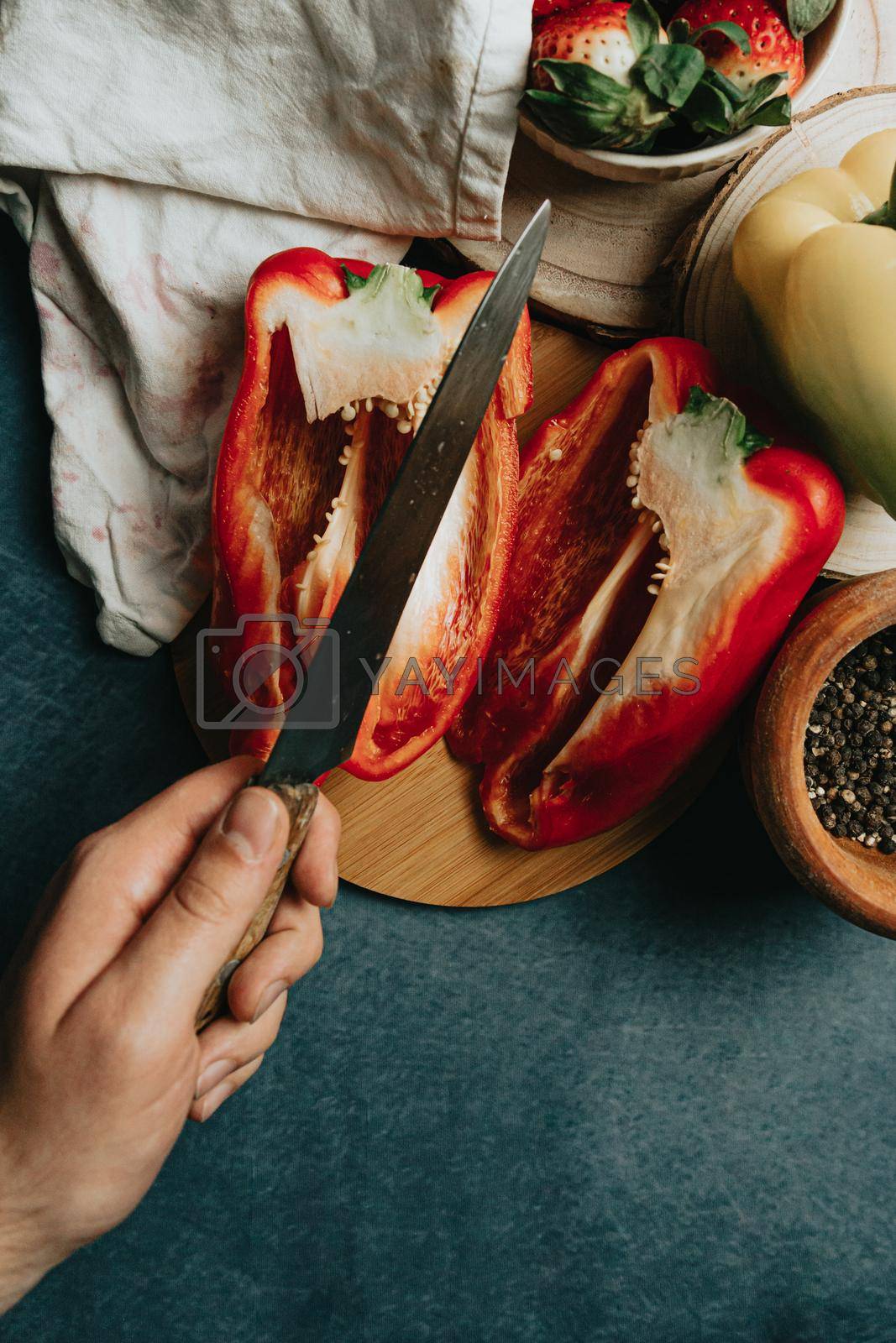 Royalty free image of Mock up of a cooking table with a pepper cut in half a knife with a hand and some condiments by AveCalvar