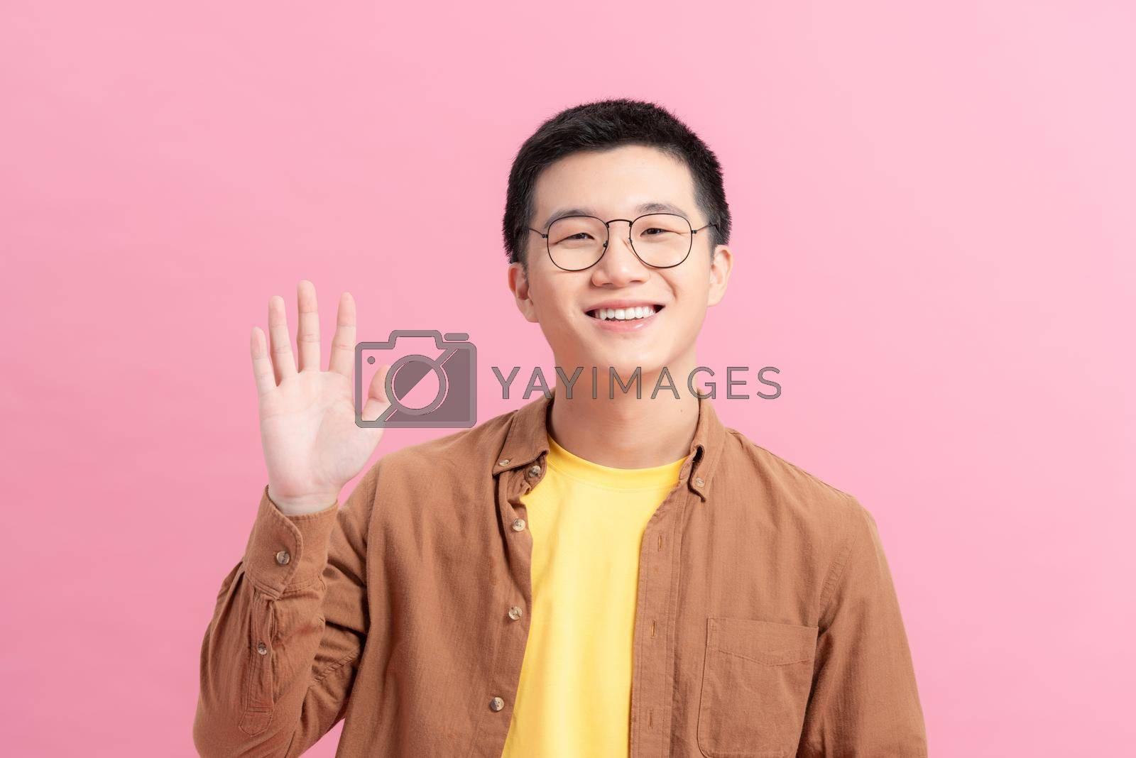 Royalty free image of Friendly modest handsome man saying hi with hesitation lifting one palm by makidotvn