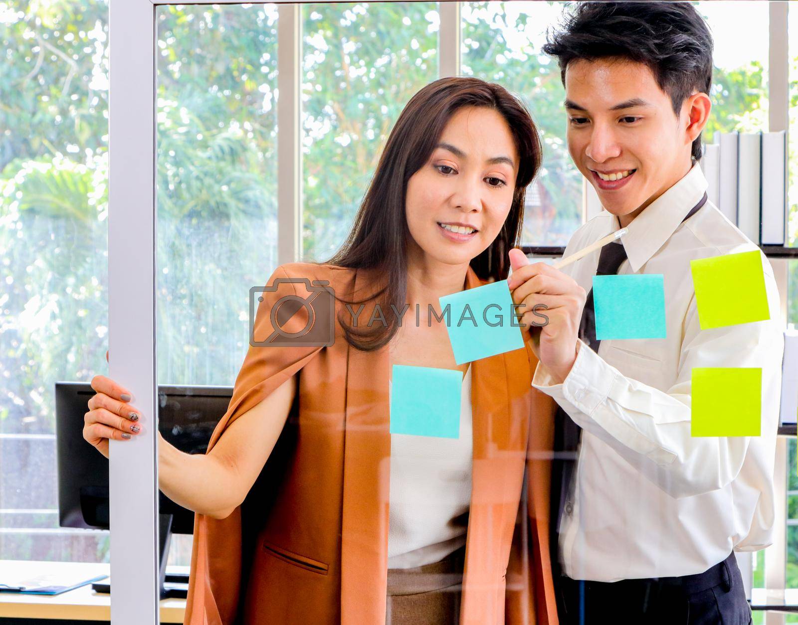 Royalty free image of Asian businessmen and women looking and writing post-it notes for brainstorming by atitaph