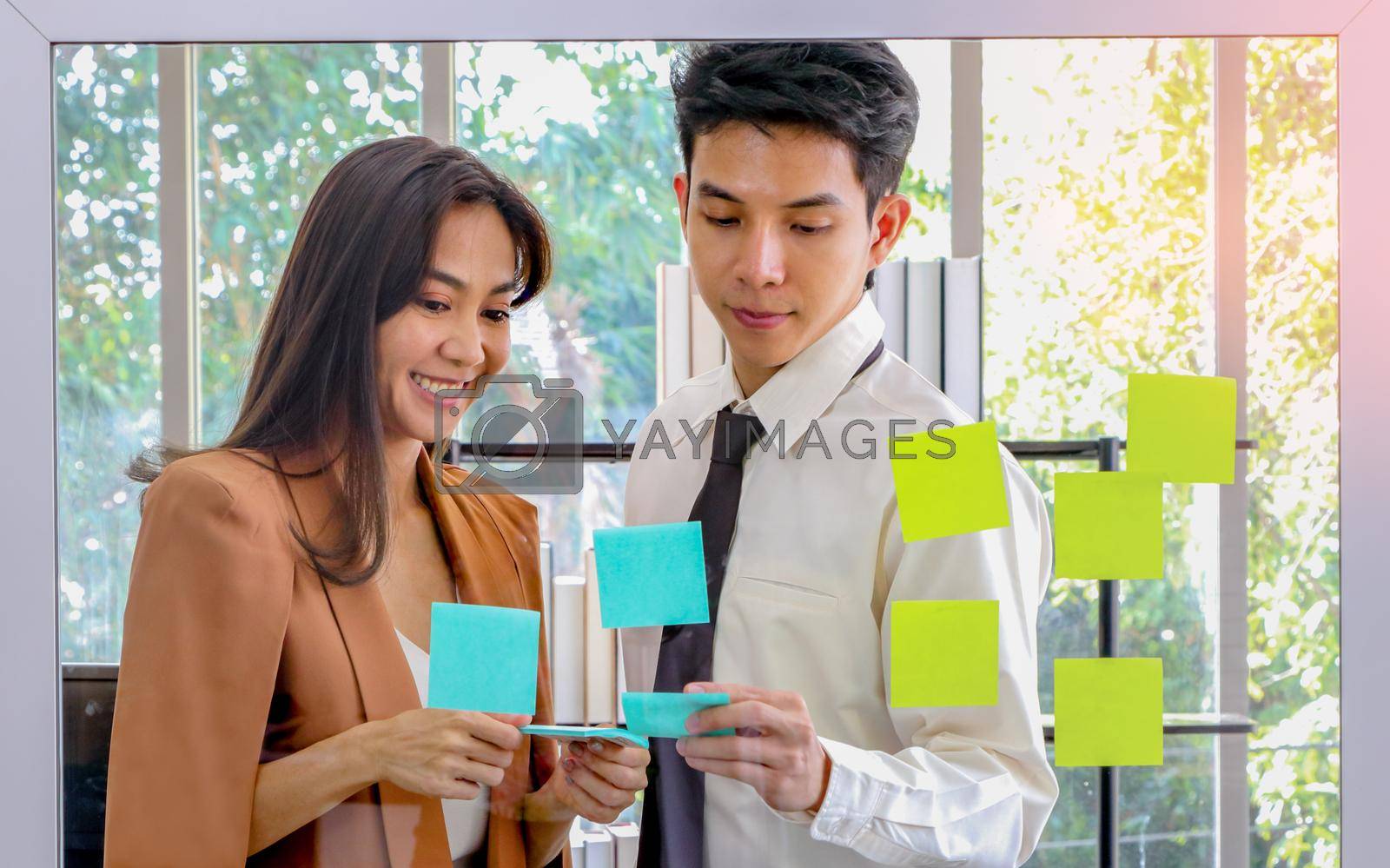 Royalty free image of Asian businessmen and women looking and writing post-it notes for brainstorming by atitaph