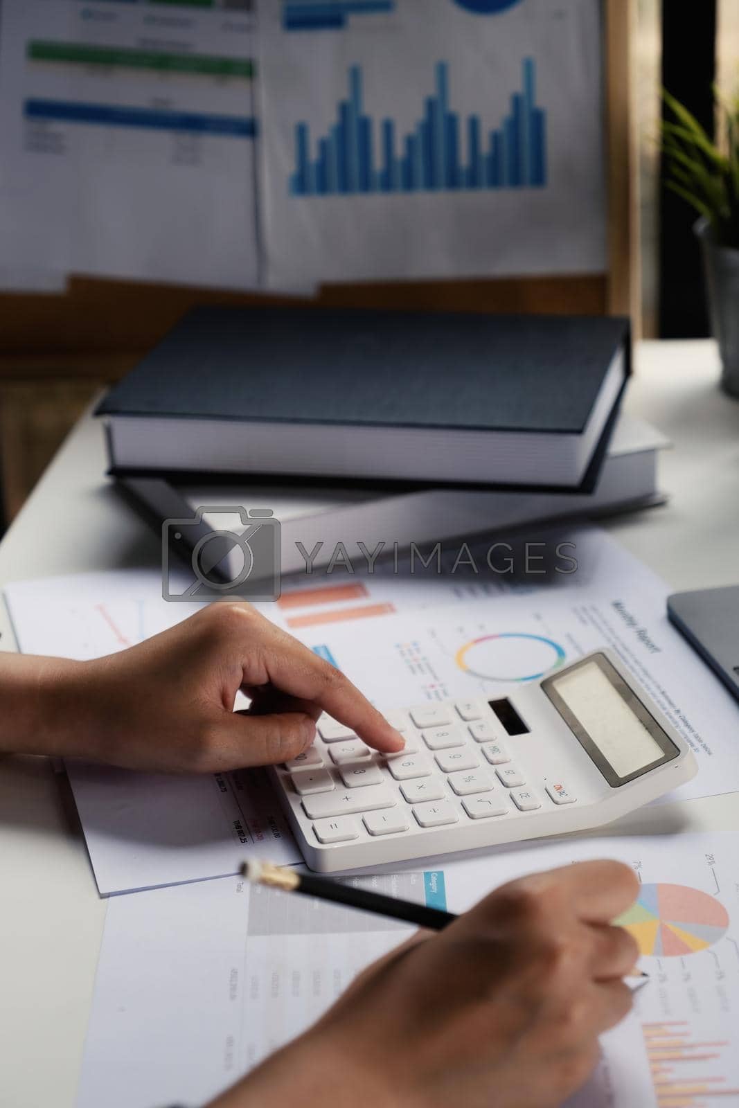 Royalty free image of A business woman accountant or banker does an audit and calculates expenses for a financial report balance sheet statement using a calculator. The principle of saving and investing. by itchaznong
